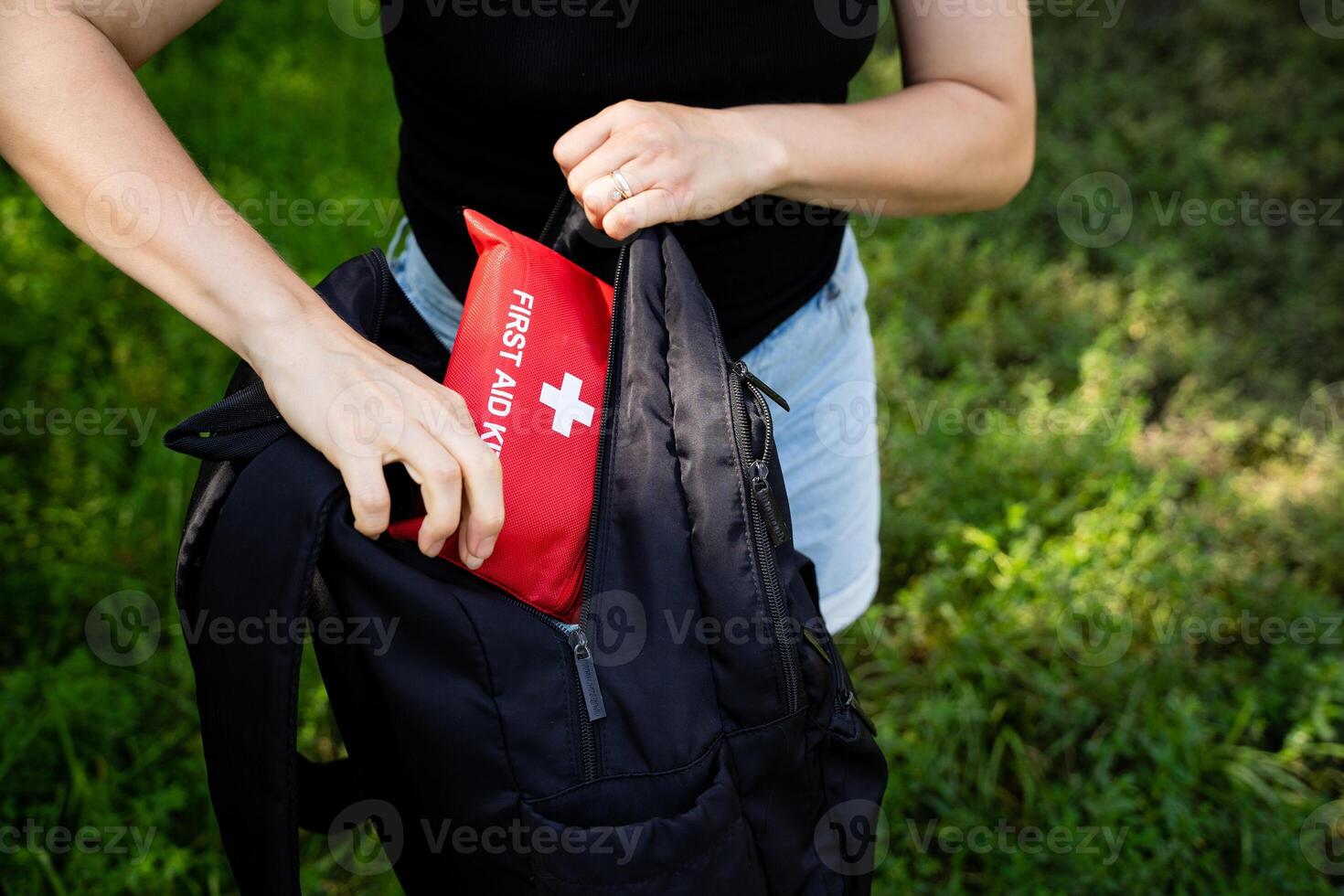 A person is packing a wellprepared first aid kit into their backpack while enjoying the beauty of nature photo