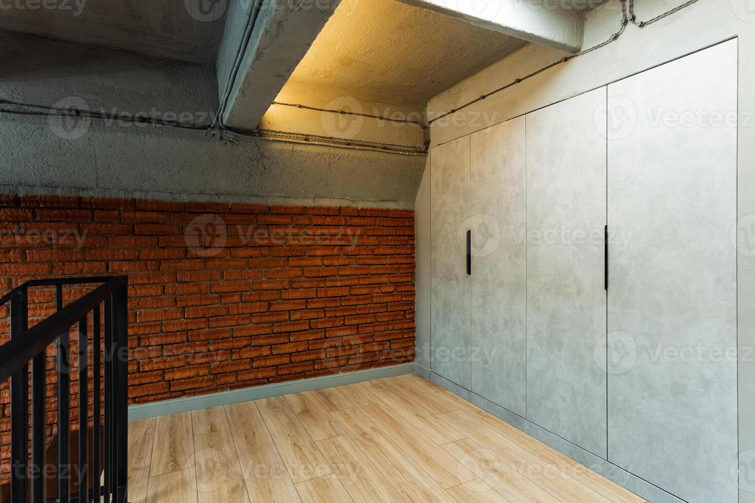 An empty room with a brick wall and a staircase photo