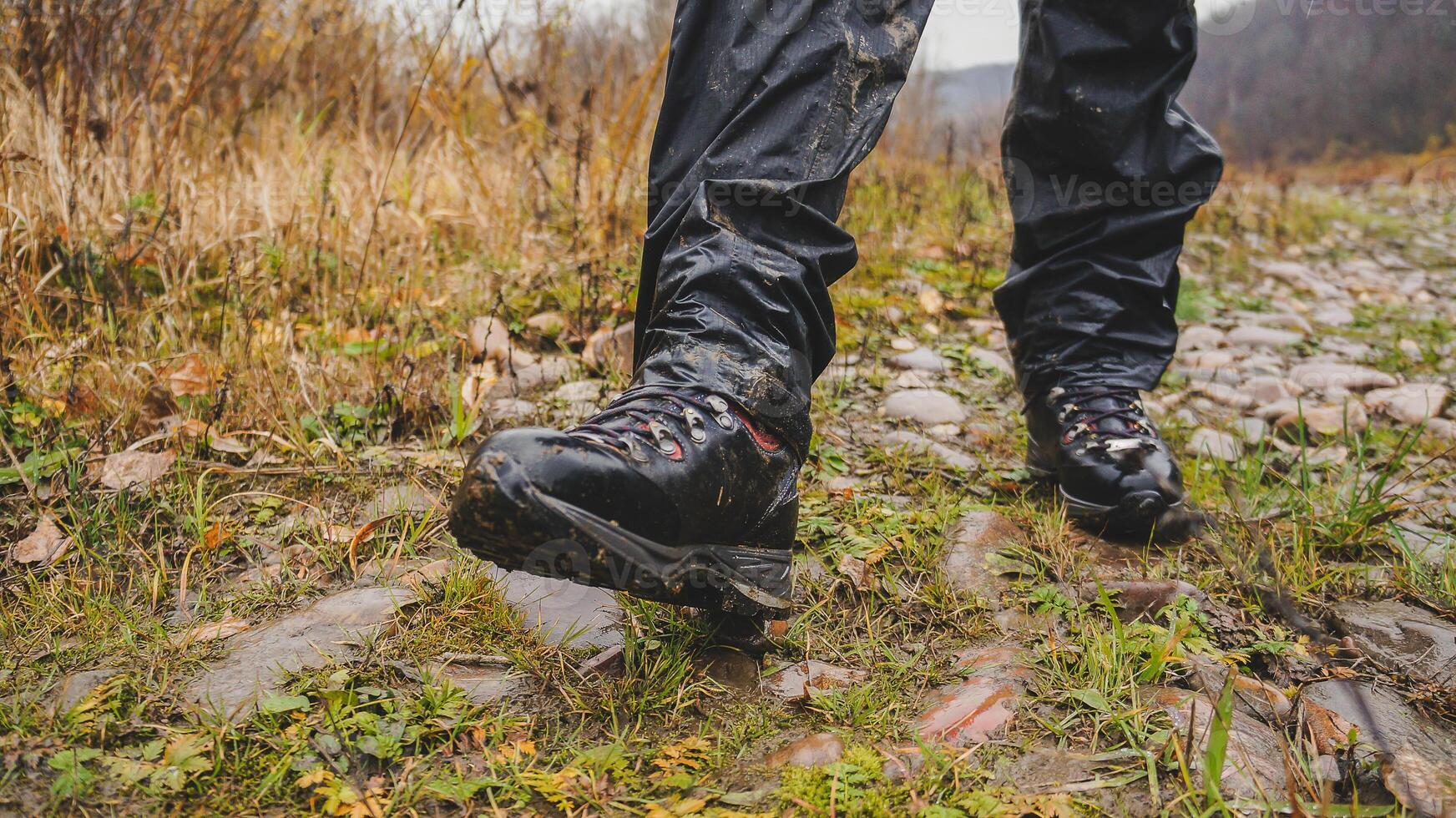 Hiker in sports gear trudging through mud on natural path with trees photo
