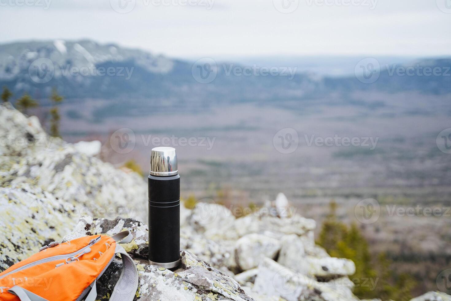 A thermos rests on a mountain, surrounded by sky, soil, and rocky landscape photo