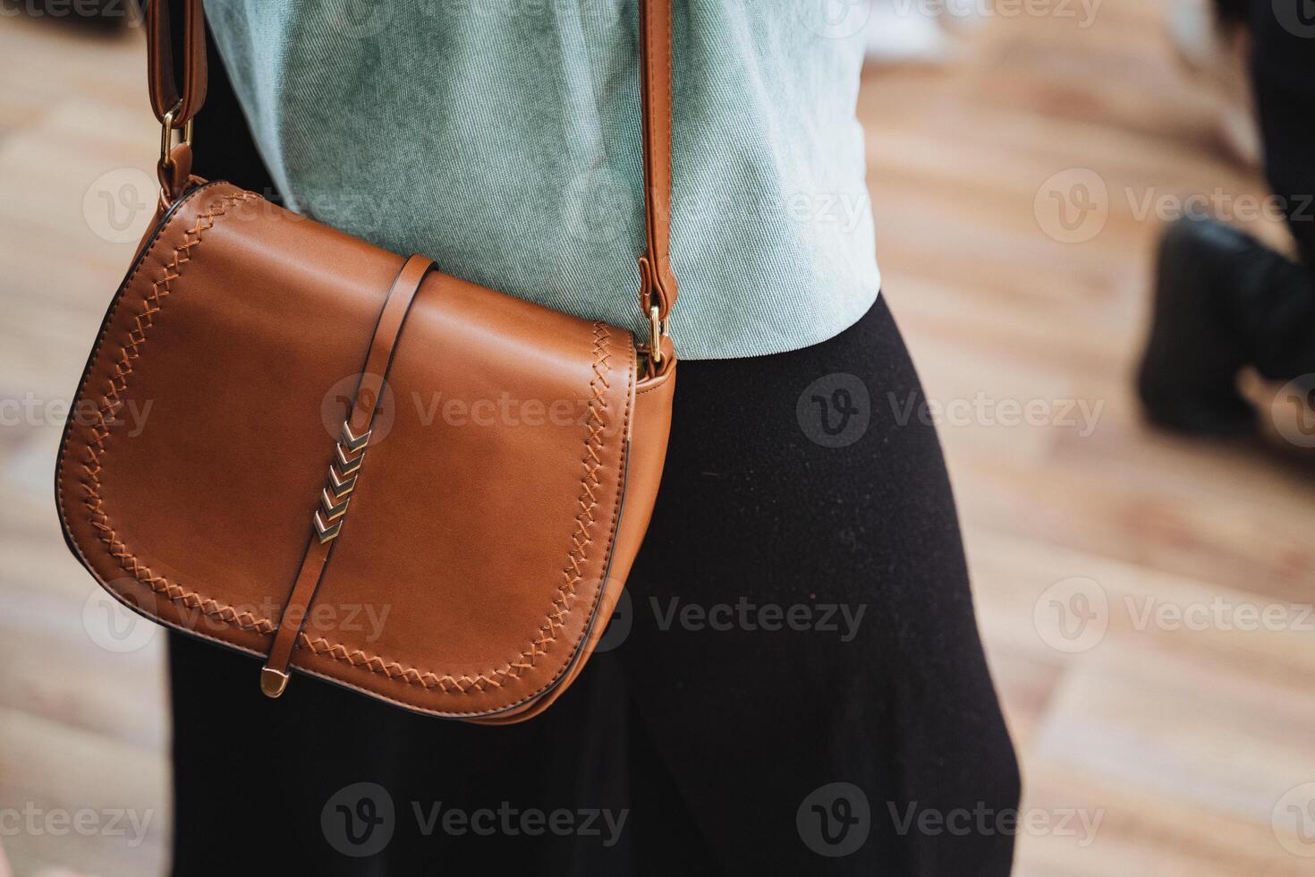 She is stylishly carrying a brown leather shoulder bag photo