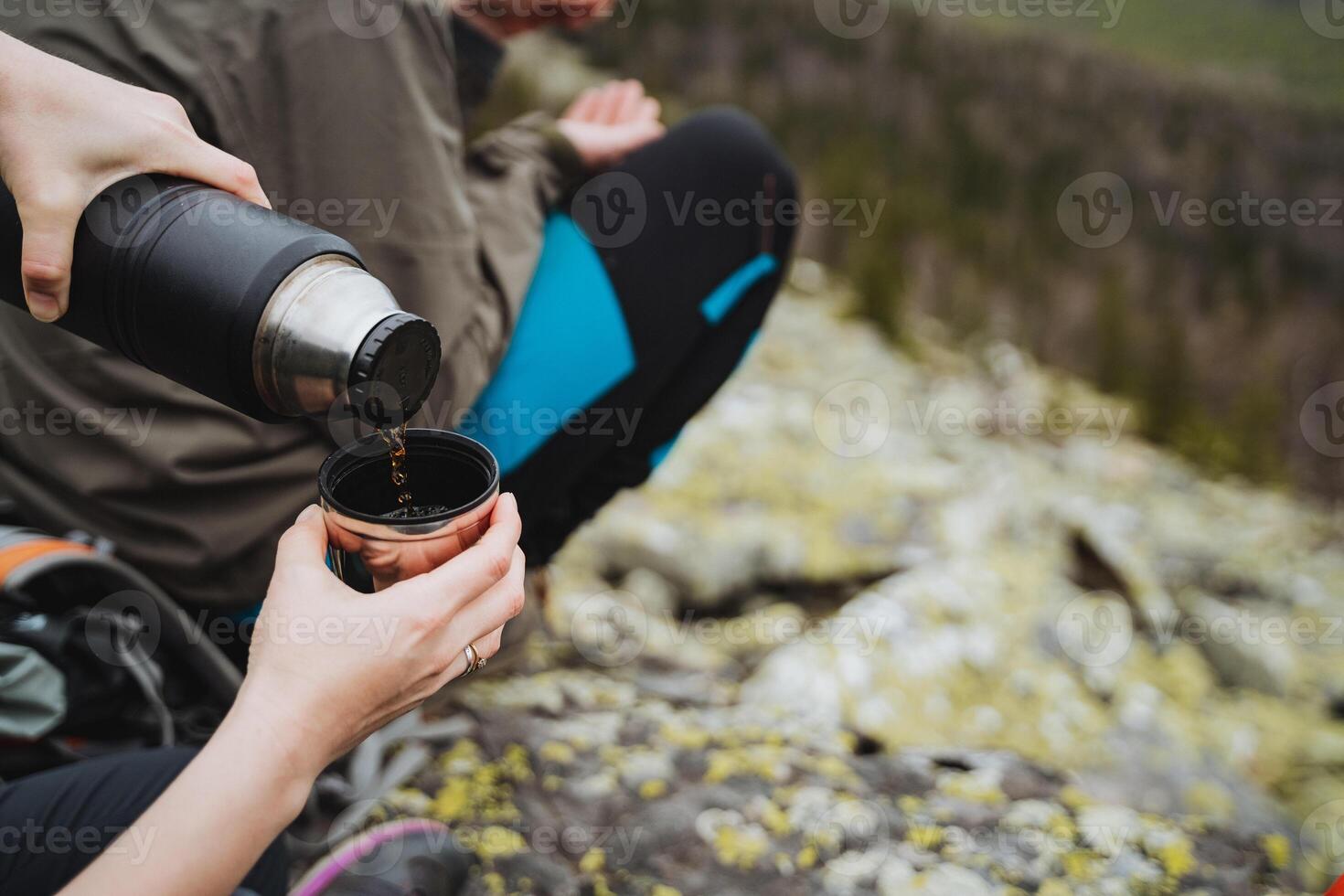 A photographer pouring coffee from a thermos into a cup photo