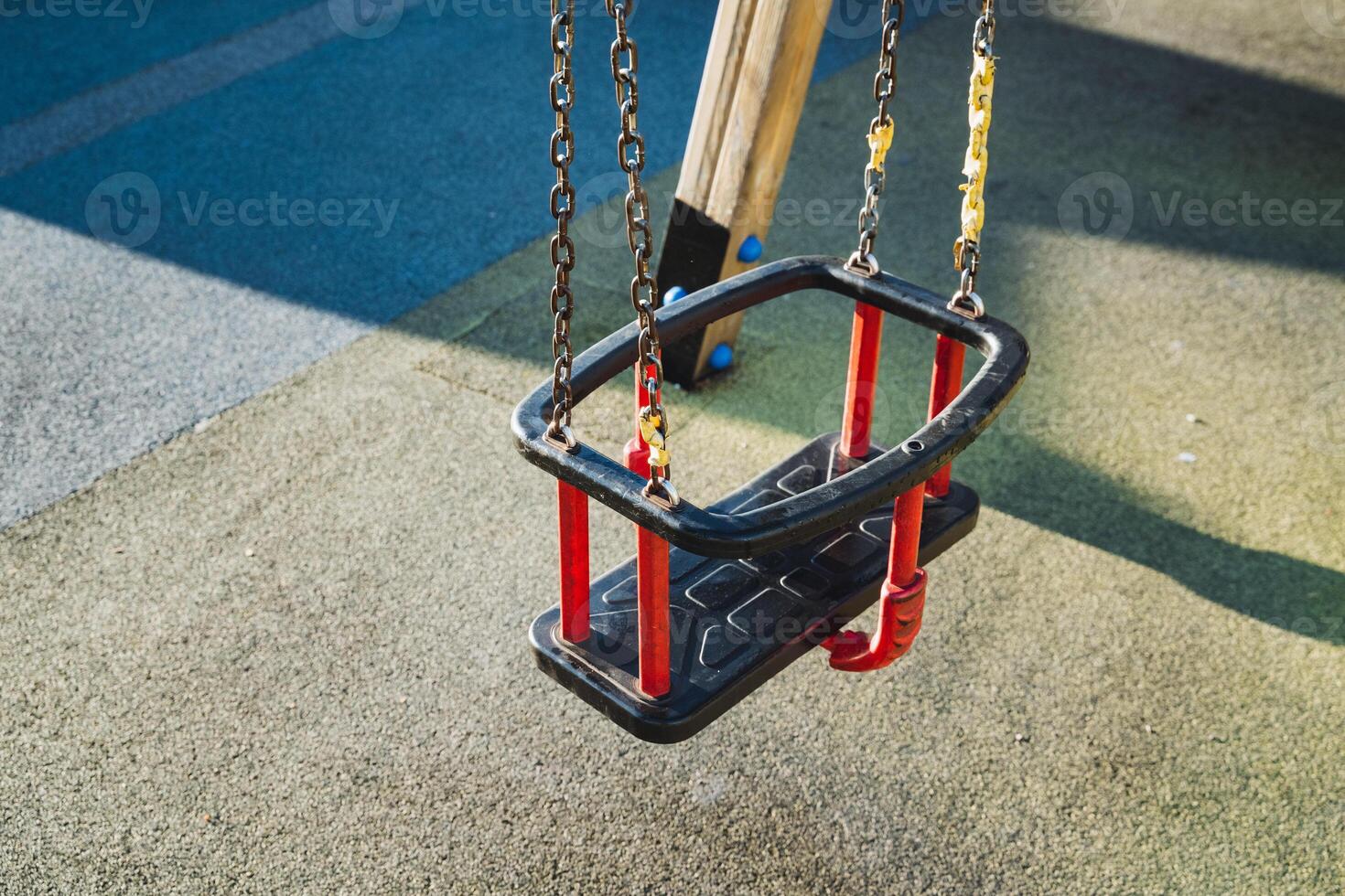 This inviting community space features a sturdy black swing with bright red handles on solid concrete, inviting all to enjoy play and relaxation, promising joy for every visitor photo