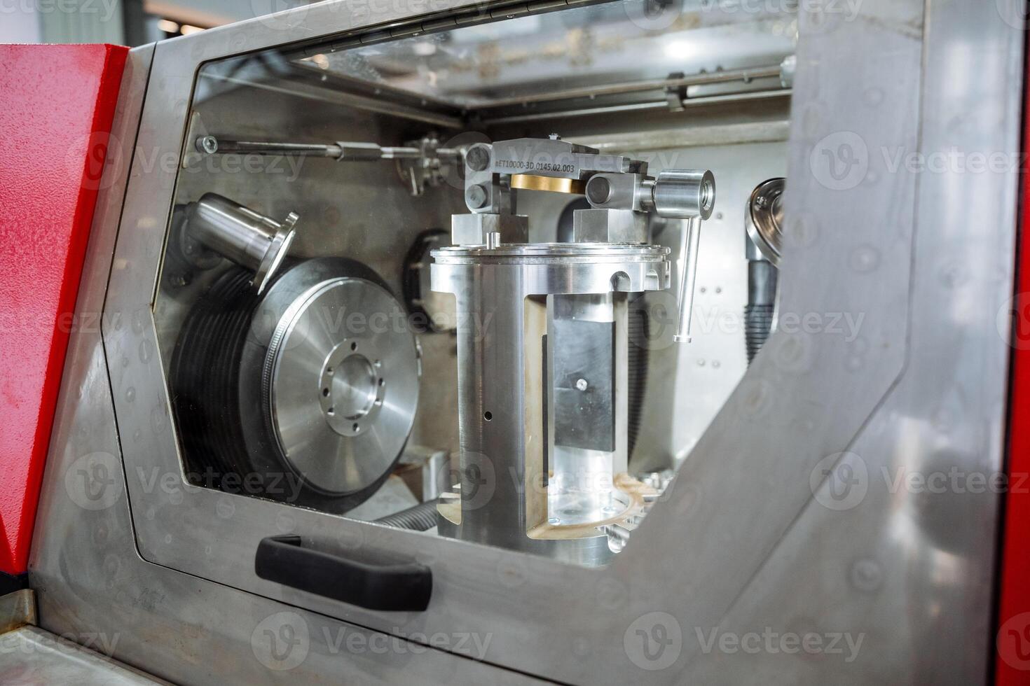 Here we see a highly detailed closeup image of a unique machine located within a factory environment, which features a striking and vibrant red door prominently displayed photo