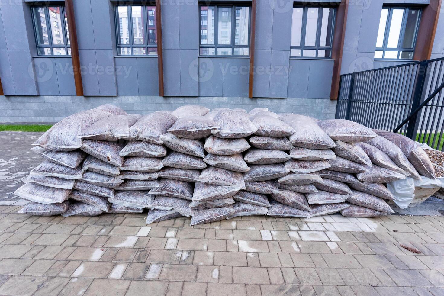 A significant stack of bags has been placed on the sidewalk adjacent to a prominent building, resulting in a striking visual contrast within the vibrant urban landscape of the city photo