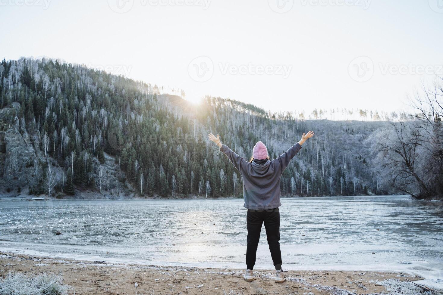 Joy, greeting a new day in the mountains against the background of the morning sun, a girl doing sports on the shore of a lake in the mountains, training in the fresh air. photo