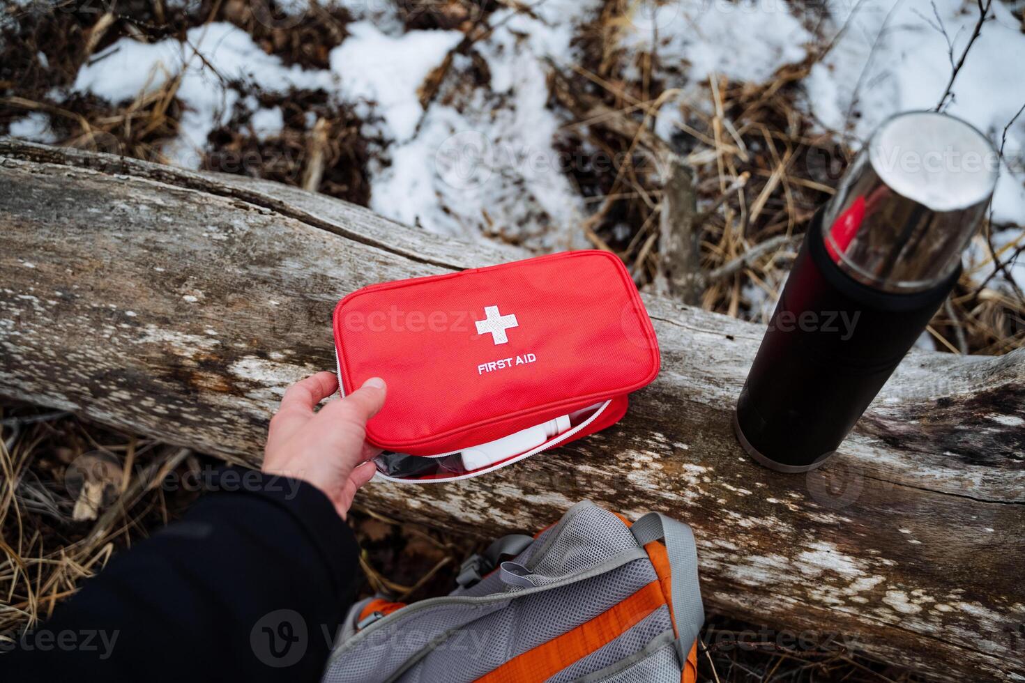 An essential first aid kit is placed on a rustic log surrounded by a picturesque winter landscape, evoking feelings of warmth and preparedness for any unexpected situation photo