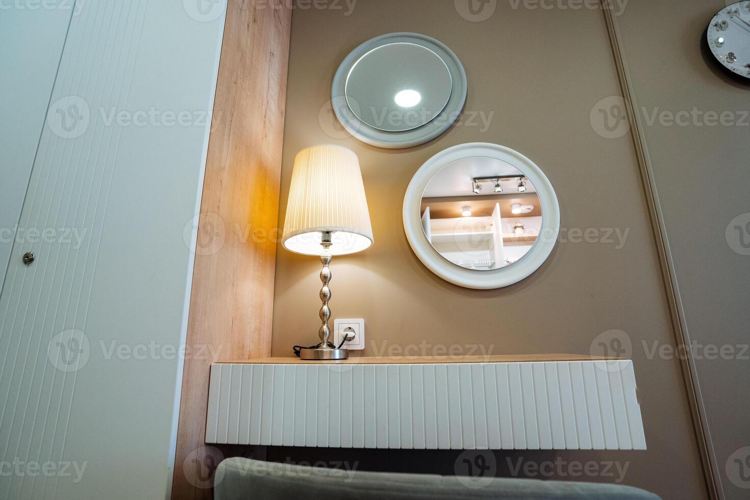 On the wall, there is both a lamp and a mirror, creating a pleasant ambiance in the room. The mirror reflects light from the lamp, enhancing the overall decor of the space photo