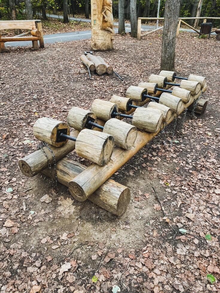 A row of wooden dumbbells made out of logs in a park photo