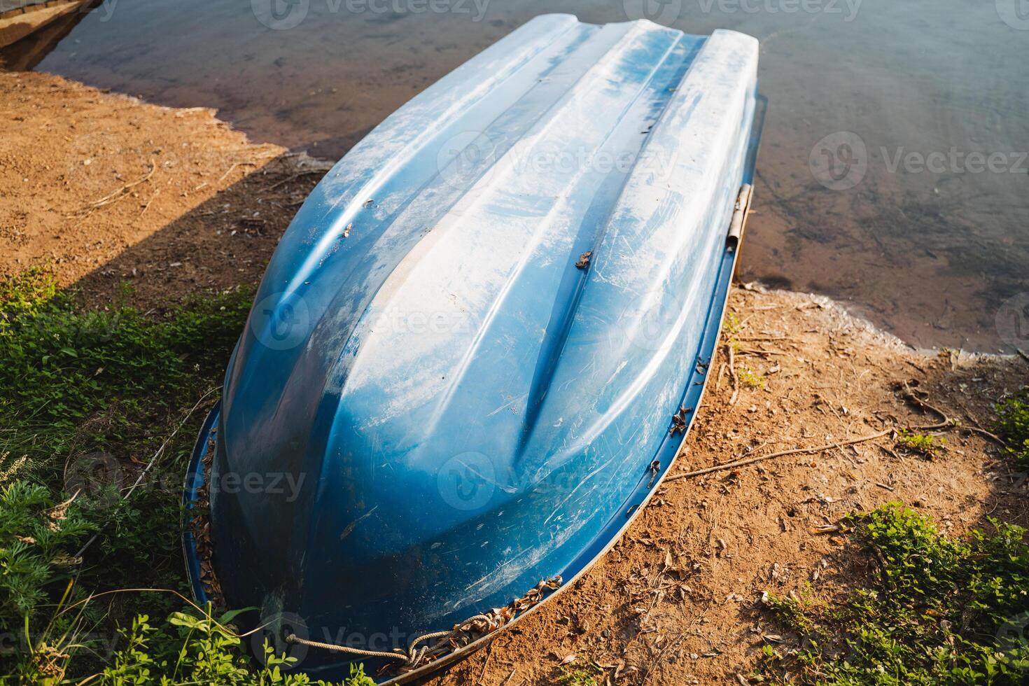 A vibrant blue boat is peacefully sitting on the shore of a beautiful lake, surrounded by nature and the tranquility of the landscape, creating a picturesque scene of calmness and serenity photo