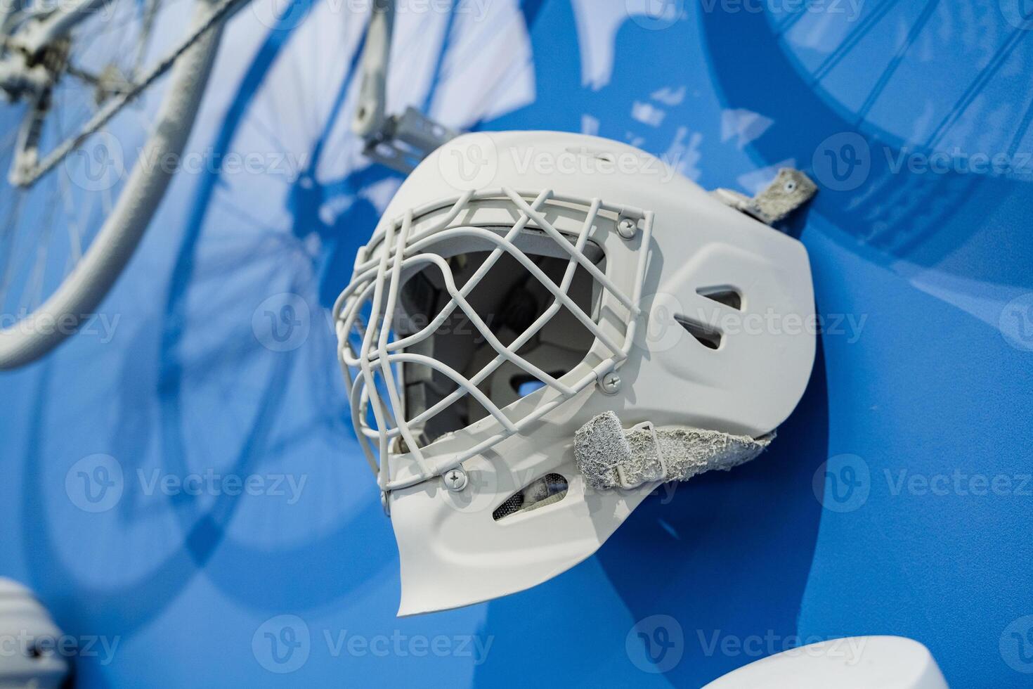 A white hockey goalie mask is beautifully mounted on a blue wall, complemented by striking silhouettes of bicycles, showcasing sports themes photo