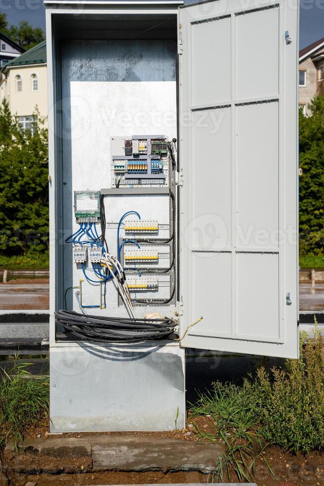 A Utility Box with an Open Door that Reveals its Internal Wiring and Associated Infrastructure Clearly Contrasting photo