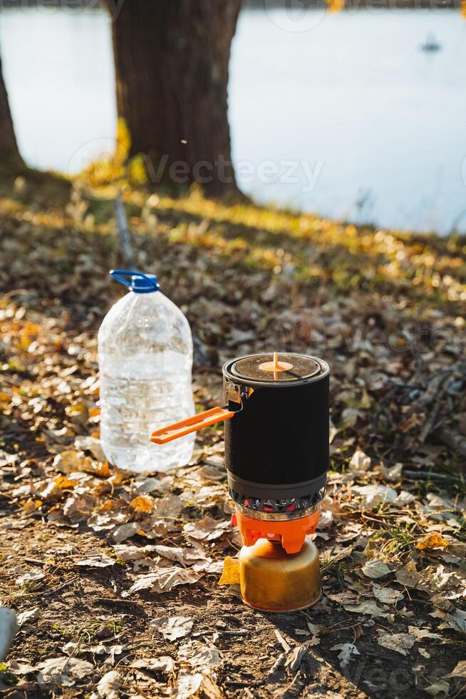Next to a stove stands a water bottle, which may be made of either glass or plastic, and there is also a pot present, indicating a potential situation where cooking might occur photo