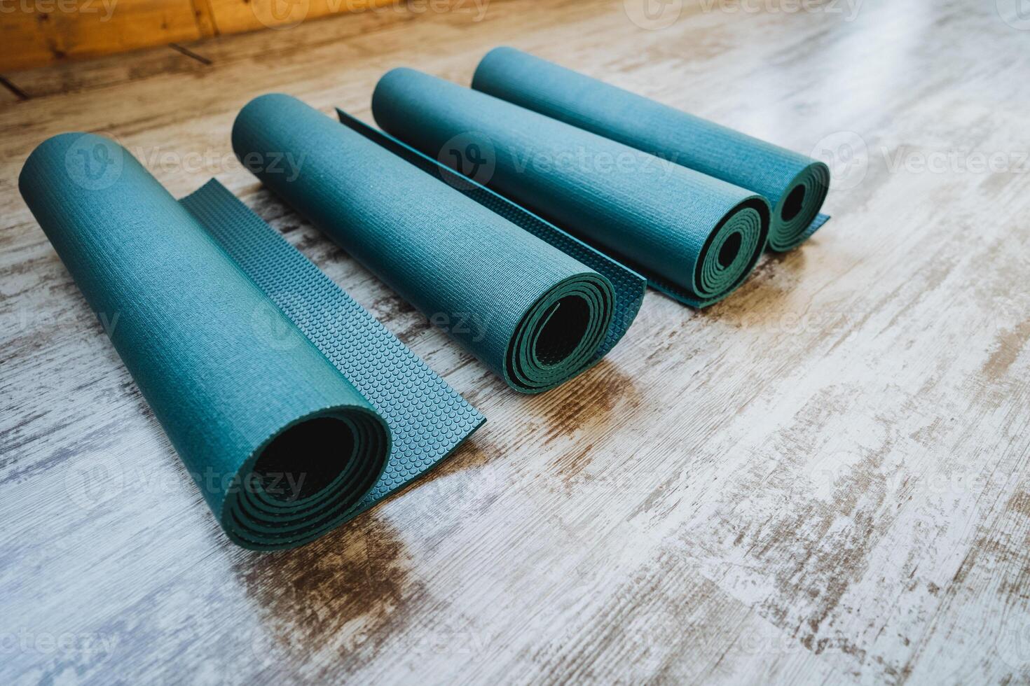 Three electric blue yoga mats neatly rolled on wooden floor photo