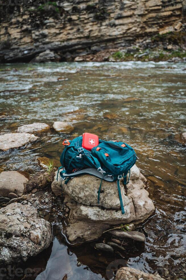 An electric blue backpack rests on a bedrock in the stream, enhancing the serene natural landscape. The wilderness setting provides a tranquil escape into the beauty of nature photo