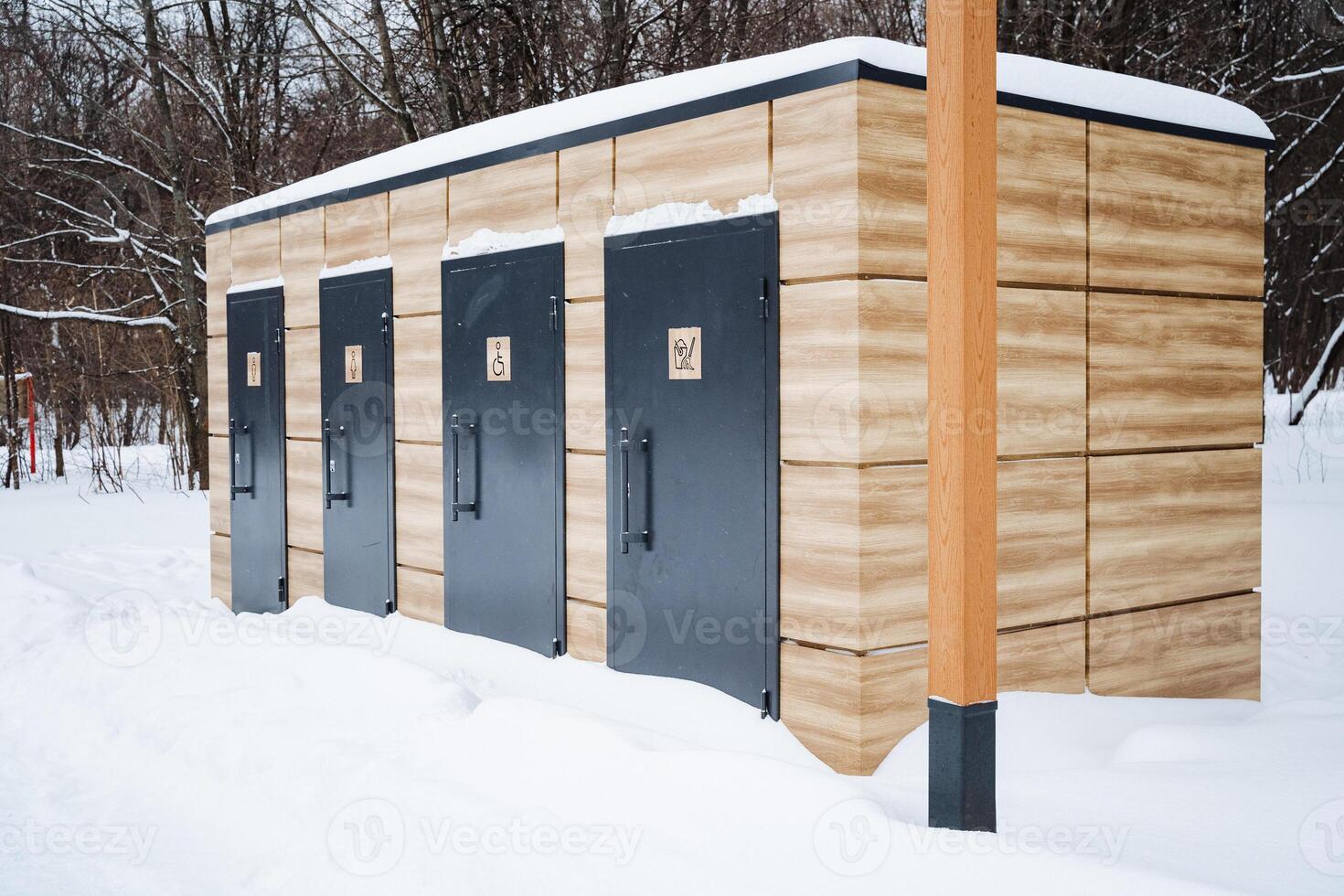 A charming wooden building, featuring striking black doors, is now beautifully covered in a thick layer of snow, creating a picturesque winter scene that feels quite enchanting photo