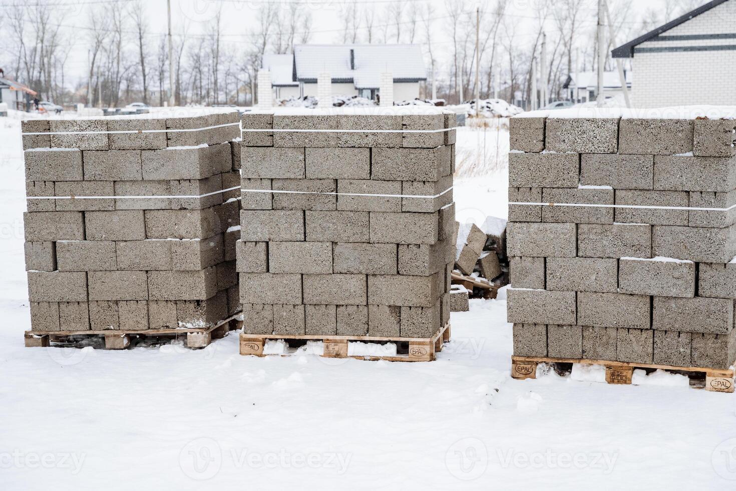 Three large pallets of bricks are carefully stacked on top of one another amidst the cold and snowy landscape, creating a noticeable contrast against the white winter scenery photo