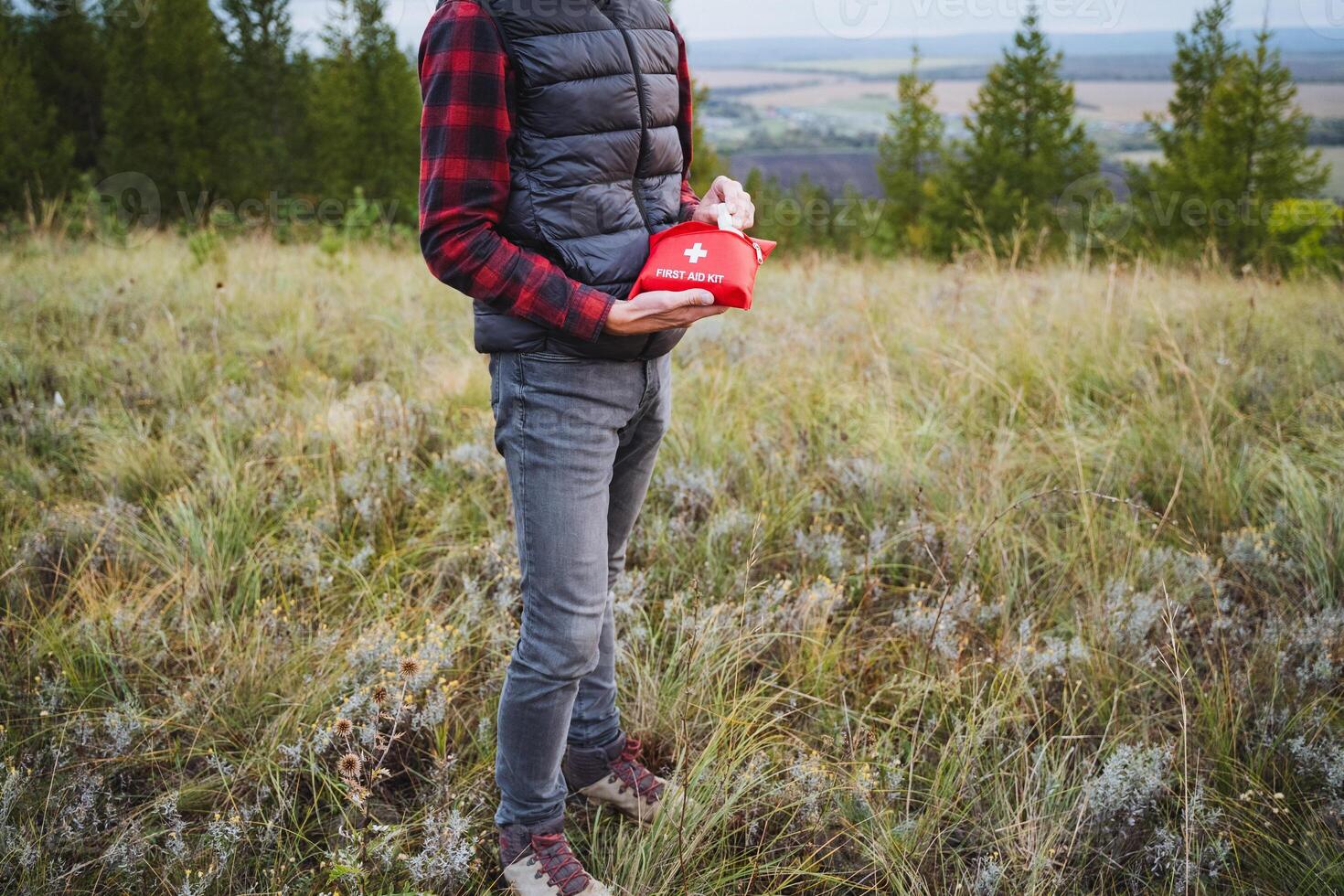 An individual is holding a first aid kit while surrounded by a breathtaking scenic outdoor landscape, ready for adventure and exploration photo