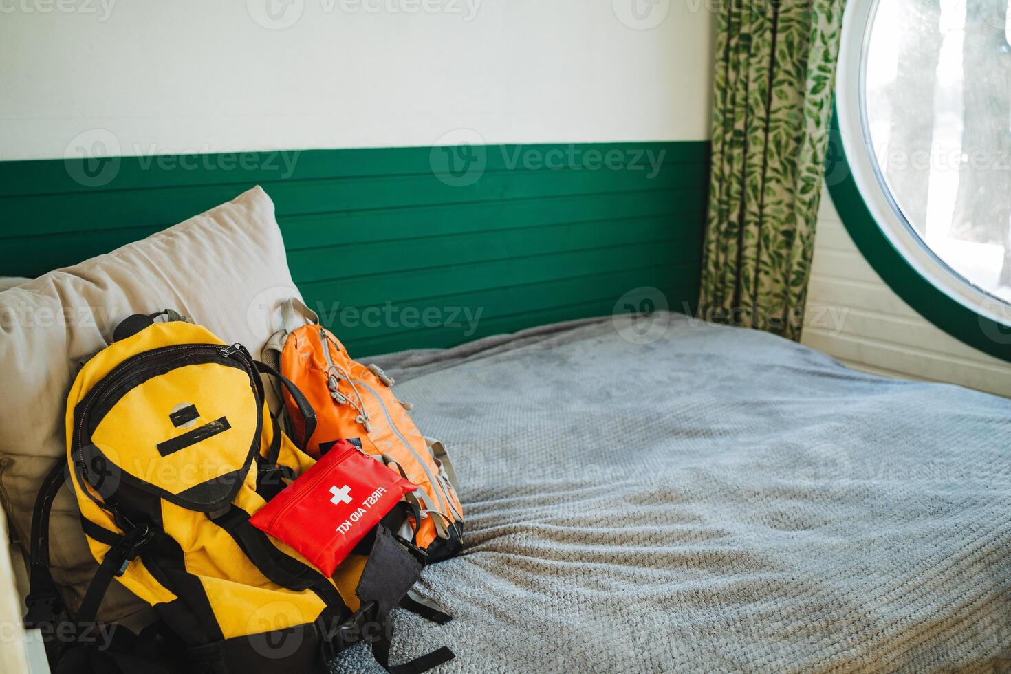 A neatly made bed is adorned with a stylish designer backpack and a wellstocked first aid kit gracefully resting on top, perfectly prepared for any adventure or emergency that may arise photo