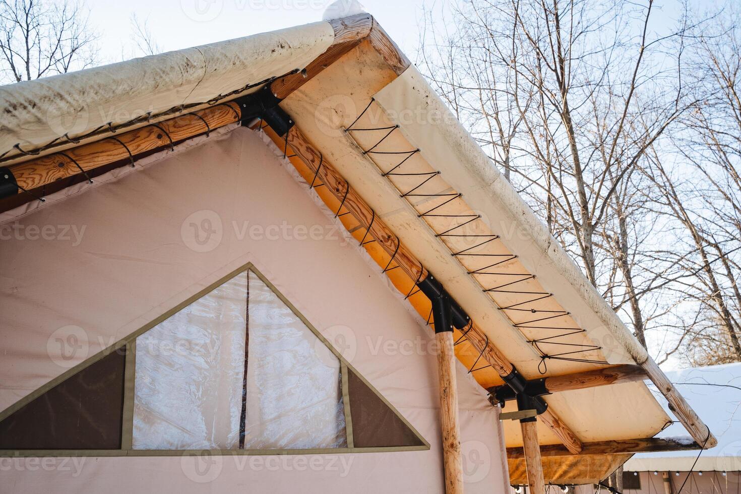 This spacious tent features a charming thatched roof and a triangleshaped window, creating a cozy atmosphere perfect for winter days and nights, ideal for a cold weather retreat photo