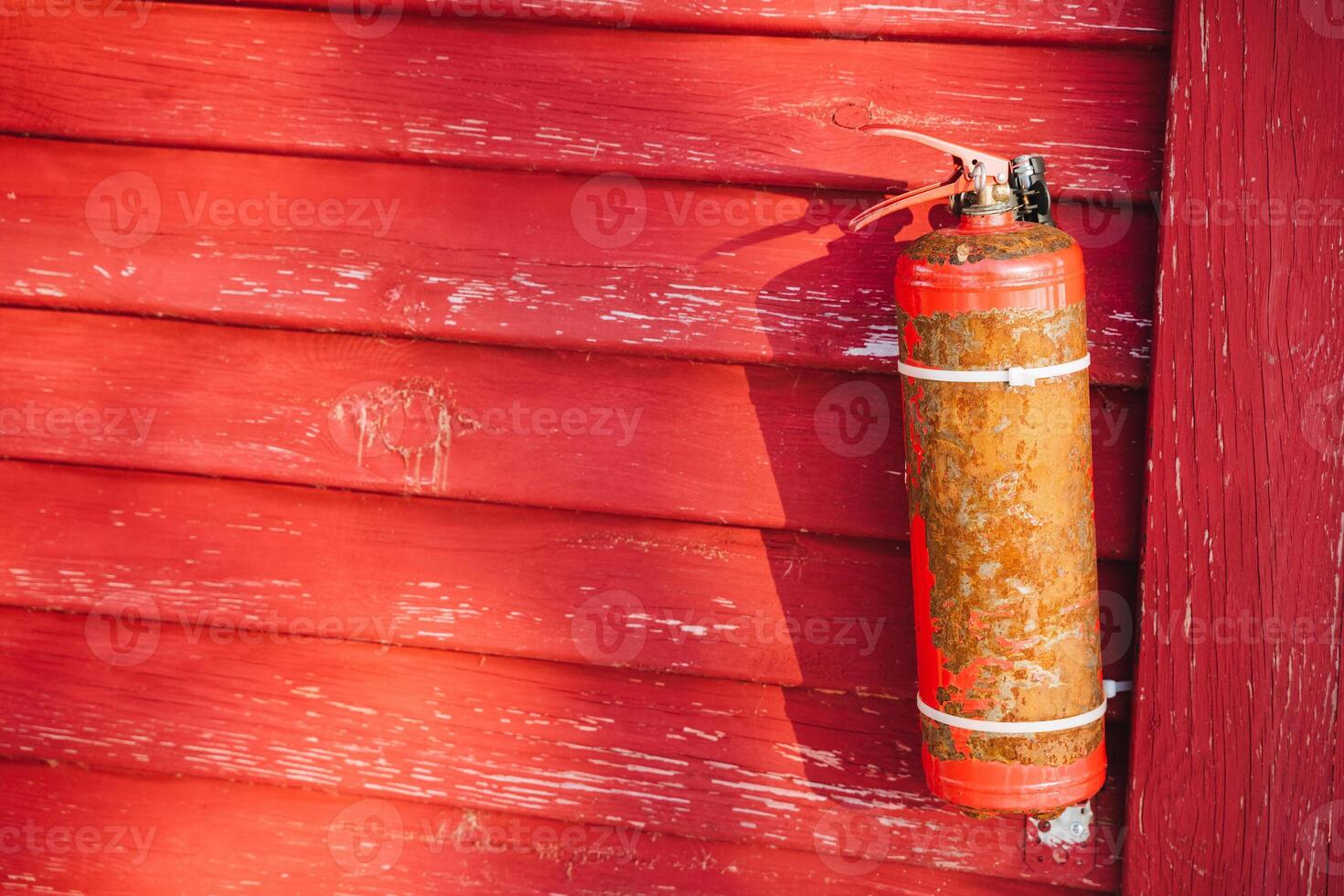 A vibrant red fire extinguisher is prominently hanging on a striking red wooden wall, creating a visually appealing contrast and serving an important safety function in the space photo