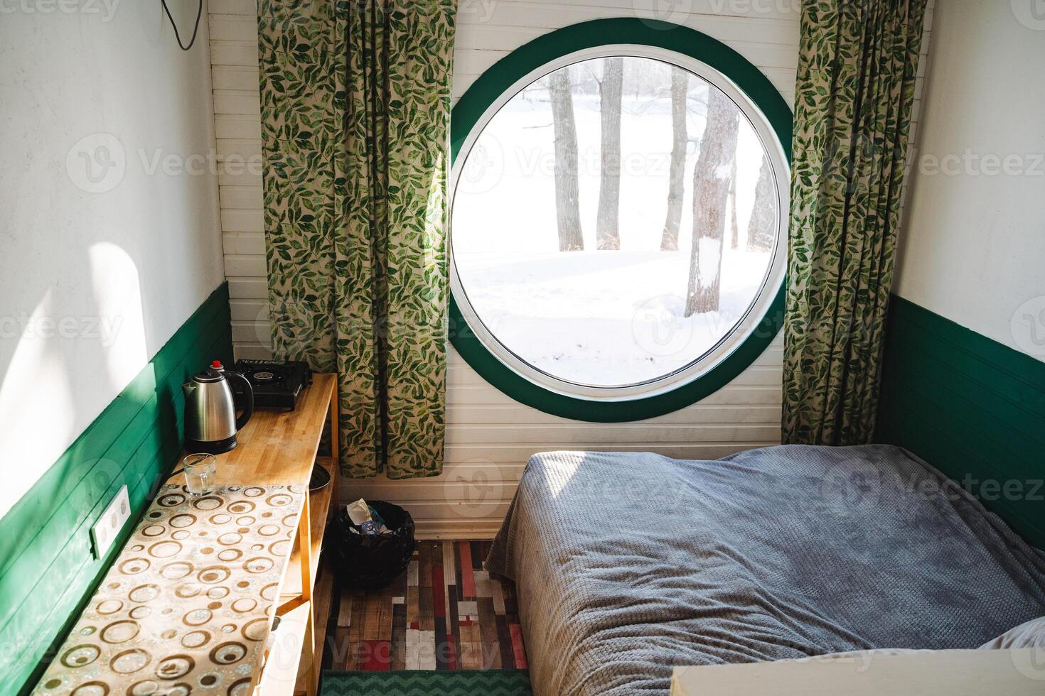 This beautifully designed bedroom has a cozy bed with soft linens and a charming round window, creating an inviting and tranquil space ideal for relaxation after a long day photo