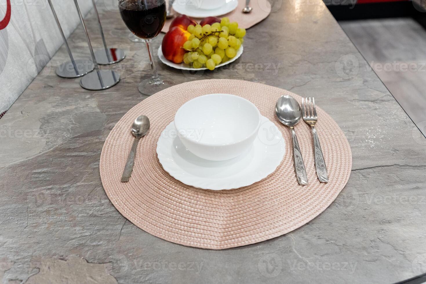 An elegantly arranged dining table showcasing exquisite plates, beautifully crafted bowls, shiny spoons, and a lovely glass of wine, all prepared for a truly delightful dining experience photo