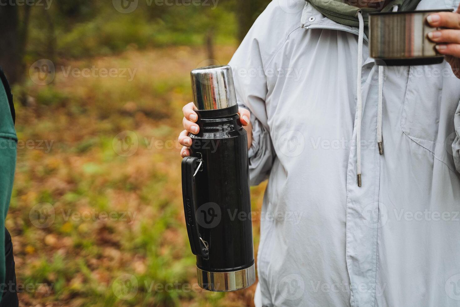 Experience a cozy outdoor gathering with a thermos and mug, surrounded by the beauty of nature, perfect for enjoying autumn with friends photo