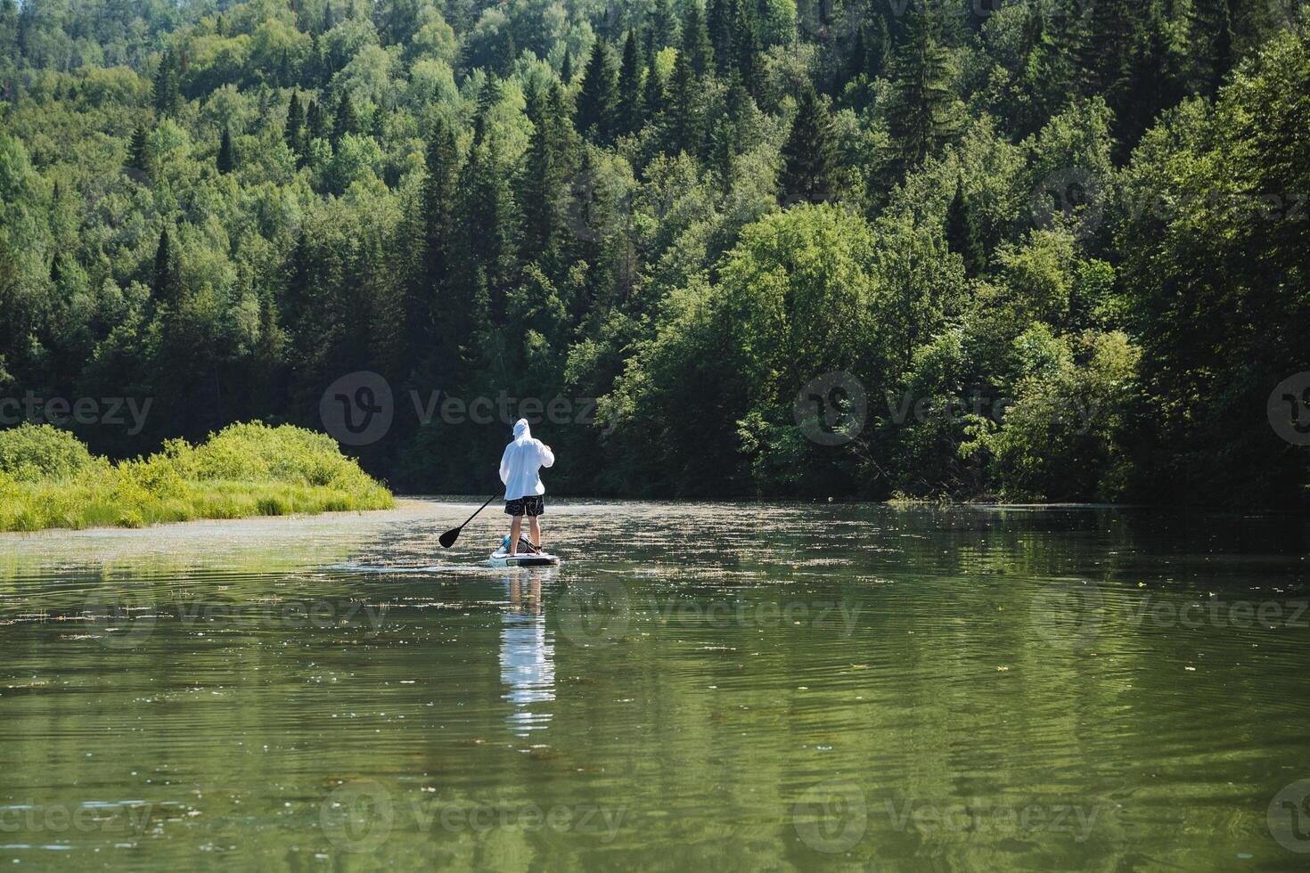 Experience inner peace while paddleboarding along a serene river, surrounded by lush forests, and connecting with nature to enjoy tranquility in a peaceful environment photo