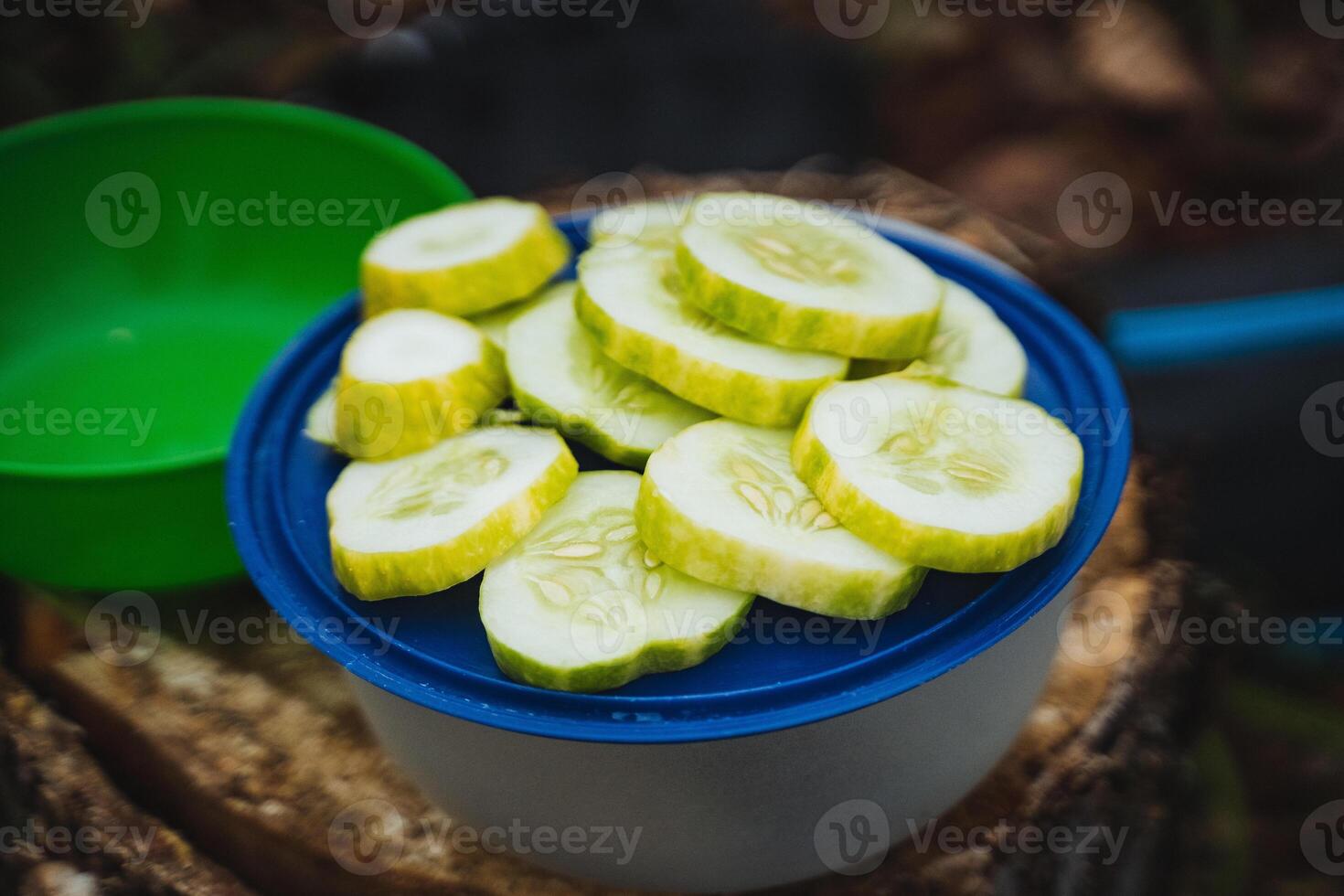 Deliciously Freshly Sliced Cucumbers are beautifully Presented in a Bowl Outdoors, Ideal for an Enjoyable and Relaxing Picnic Experience in Nature photo