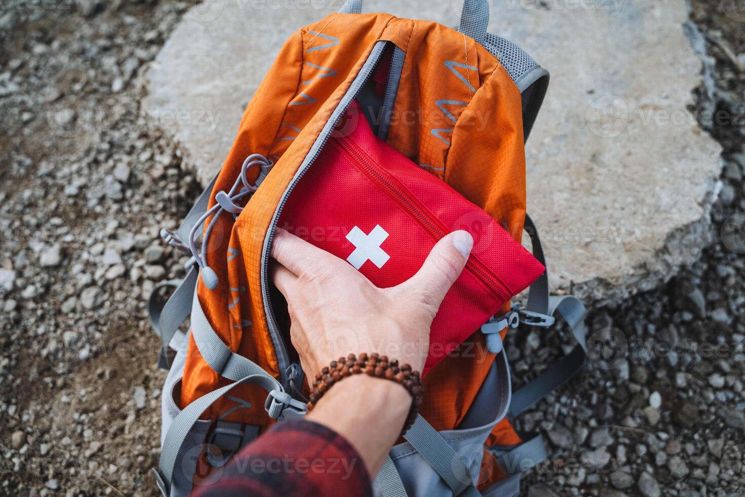 A dedicated hiker is thoroughly preparing for an exciting outdoor adventure, ensuring they have a first aid kit safely packed in their backpack photo