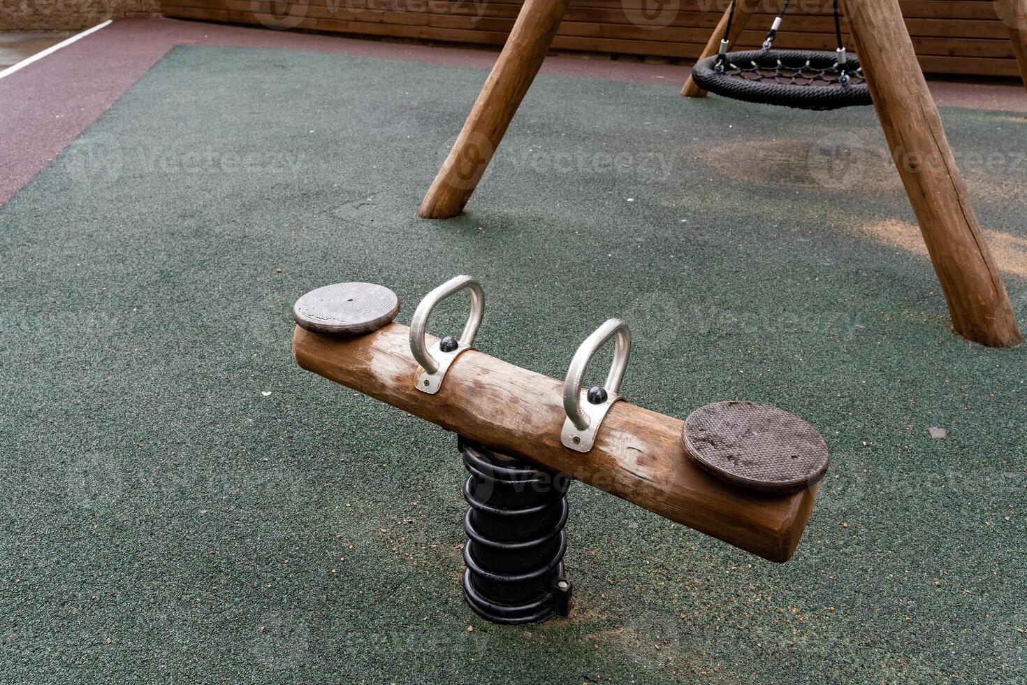 A beautifully crafted wooden seesaw is placed on a vibrant green rubber mat, making it a fun and safe addition to the playground for children to enjoy playtime and recreation photo