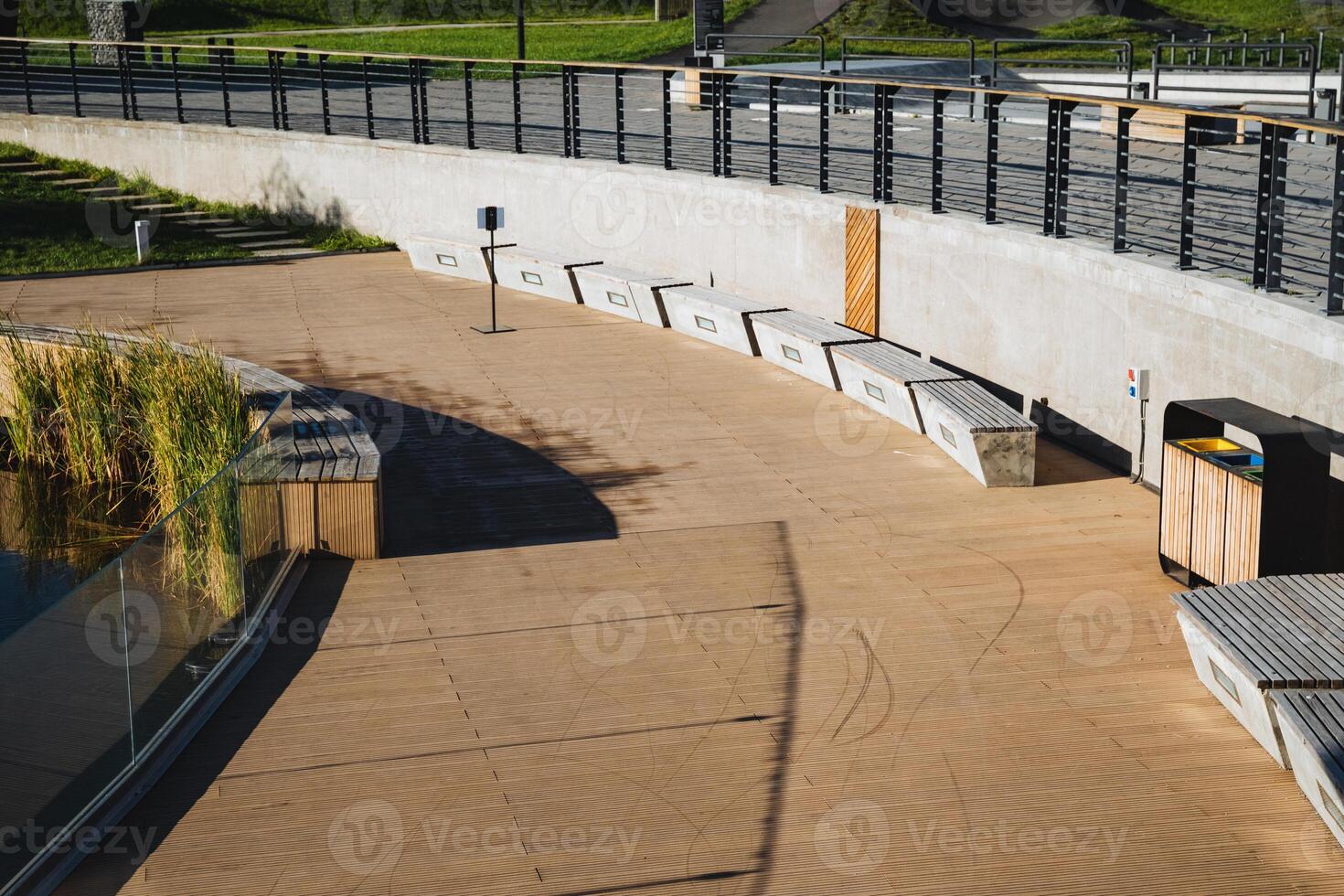 A wellconstructed concrete walkway featuring several benches along its sides, complemented by a sturdy fence that provides additional structure and safety in the background photo