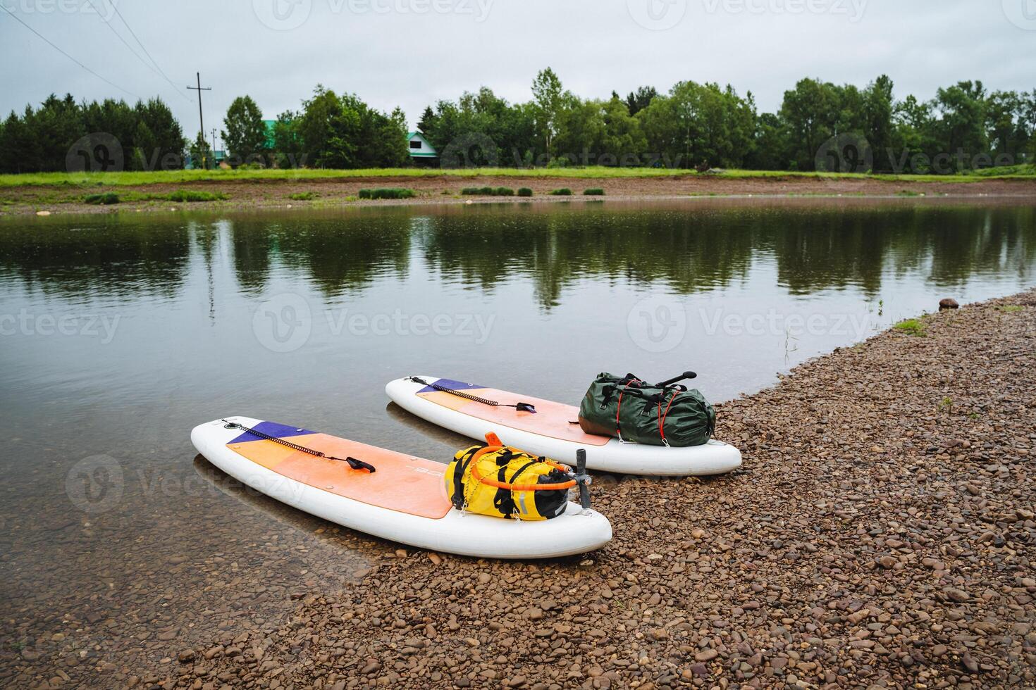 Two paddle boards by a peaceful lake, under the open sky, surrounded by beautiful nature. The tranquil setting is enhanced by the watercraft blending harmoniously with the environment photo