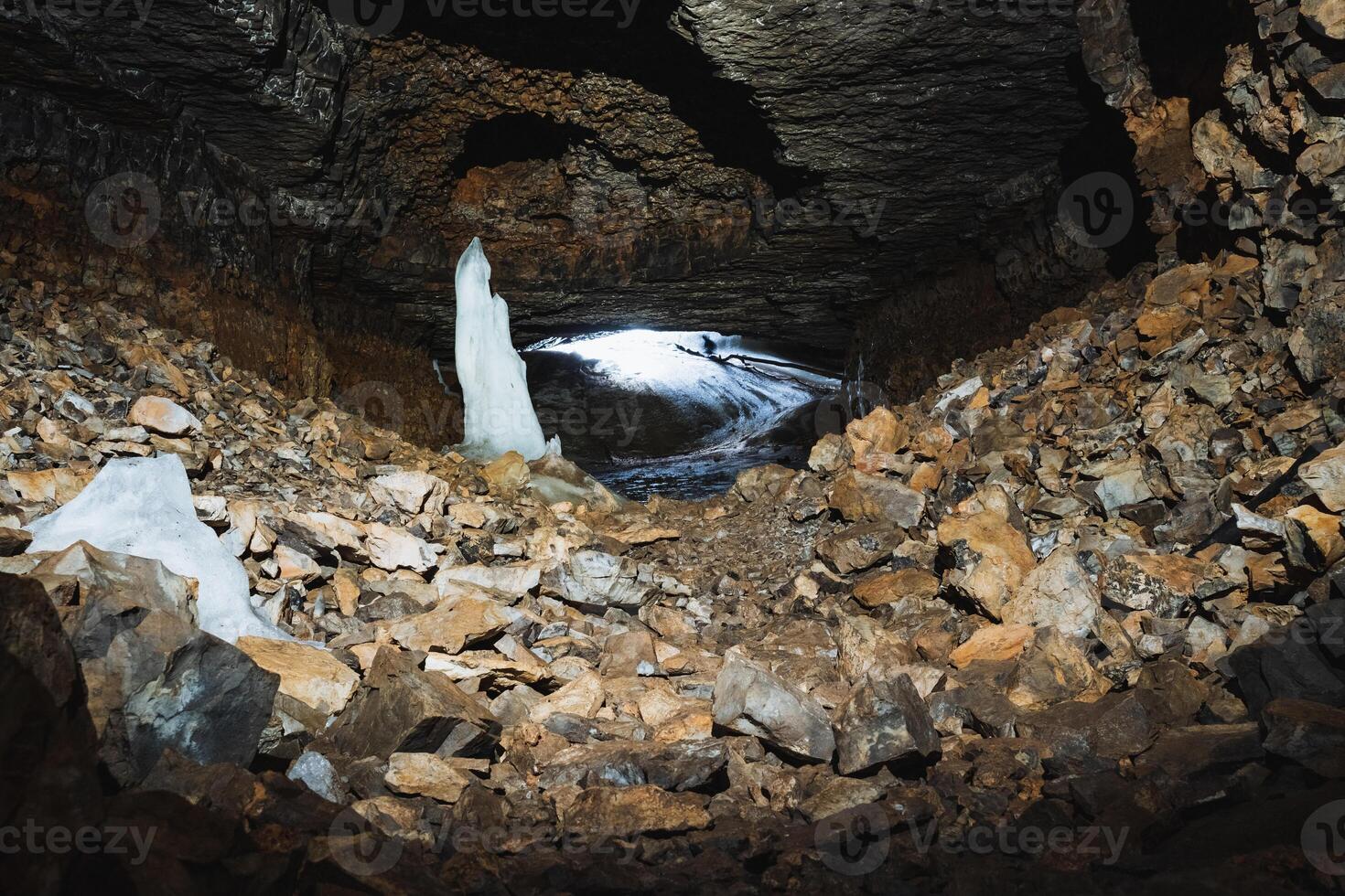 There exists a fascinating cave that features a stunning, large ice sculpture positioned right in the center of it, surrounded by natural beauty. Its presence captivates all who enter photo