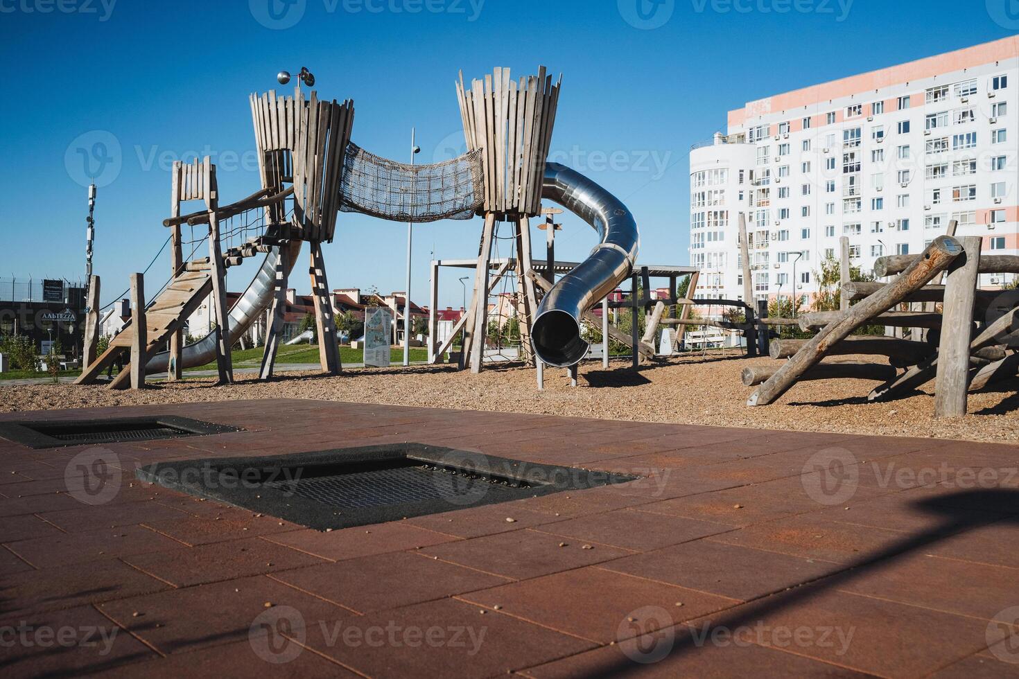 There is a vibrant playground featuring a large trampoline located right in the center of the area, surrounded by various recreational facilities and play equipment for children photo
