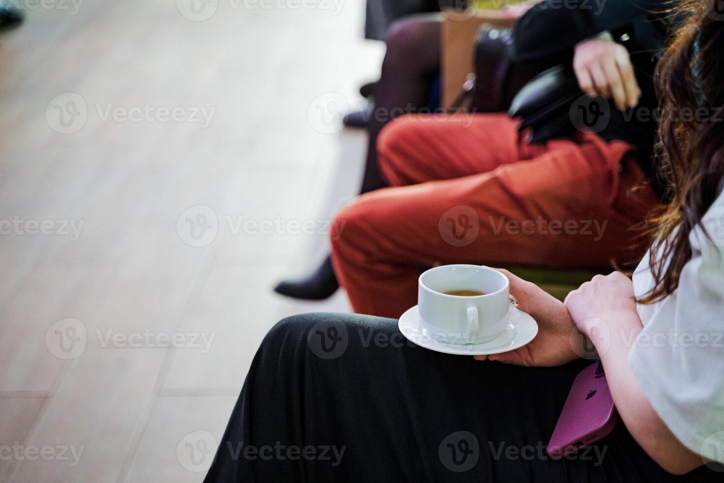 A woman sitting, holding a coffee cup in her hand photo