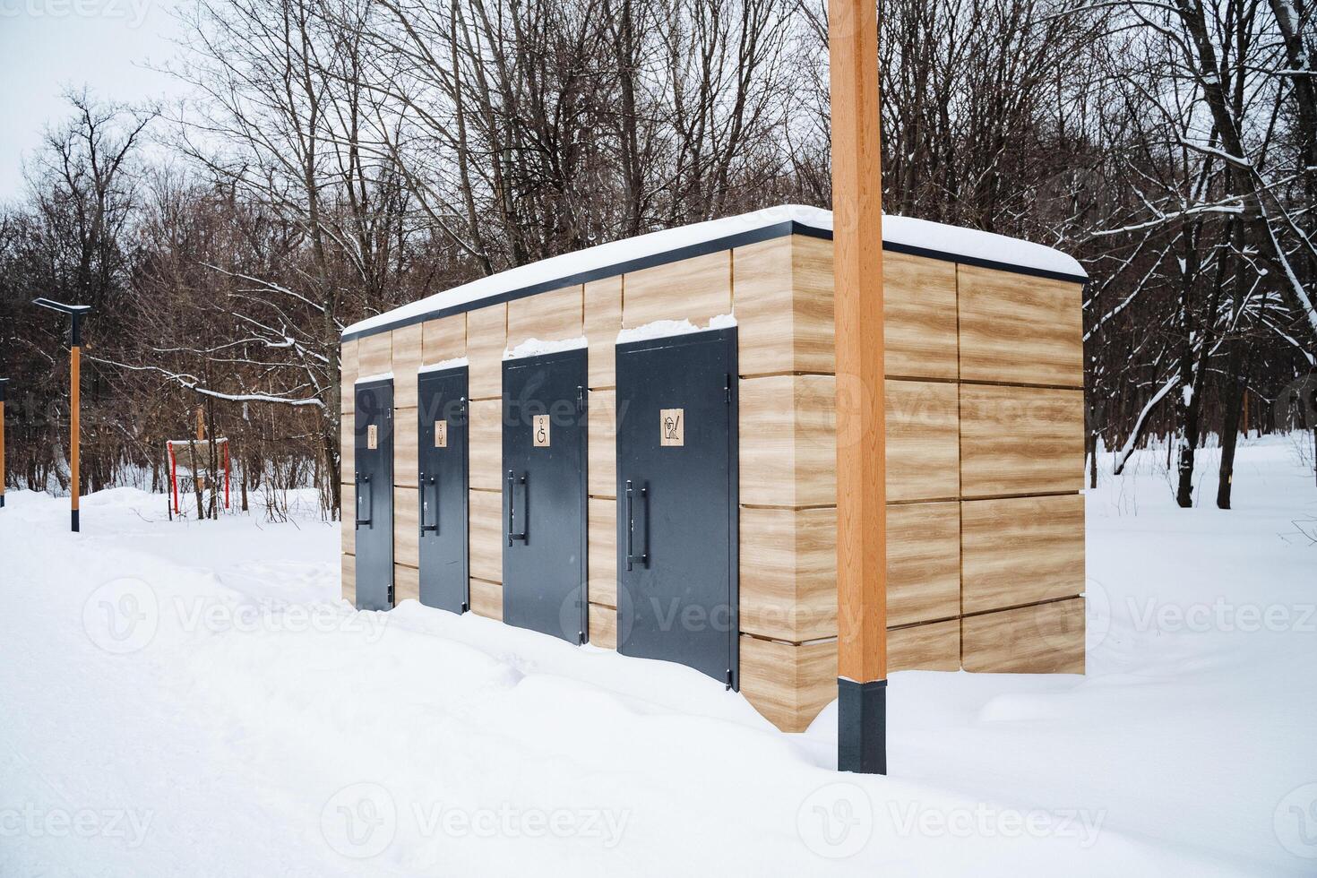 A rustic wooden cabin featuring black doors is blanketed in a thick layer of fresh, pristine snow, greatly enhancing the enchanting winter charm of this serene and tranquil landscape photo