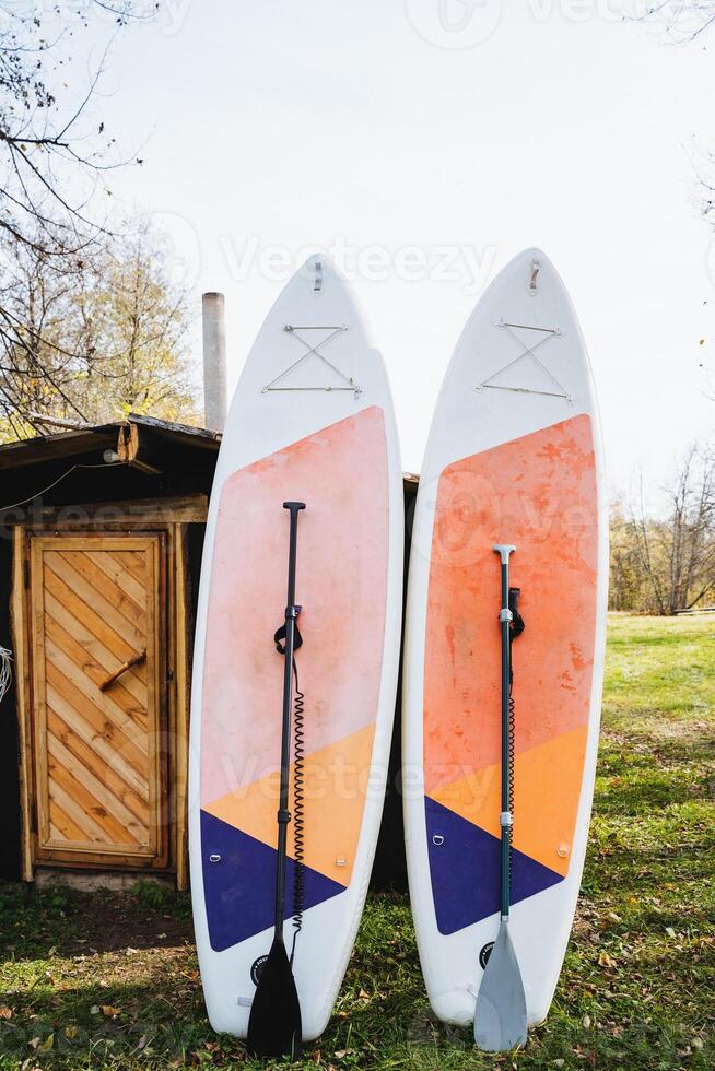 In a serene outdoor setting, two surfboards accompanied by paddles are positioned side by side on the lush green grass, creating a perfect scene for any surfing enthusiasts adventure photo