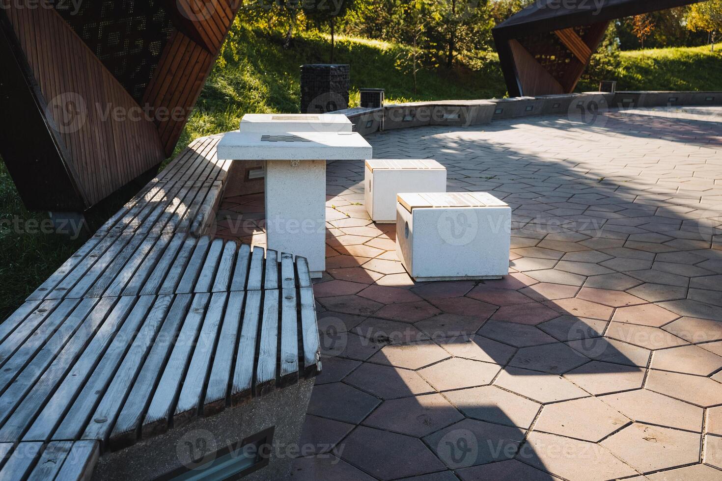 In a beautifully landscaped park, a rustic wooden bench, a charming table, and cozy ottomans come together to create the perfect spot for relaxation amidst natures ever serene beauty photo