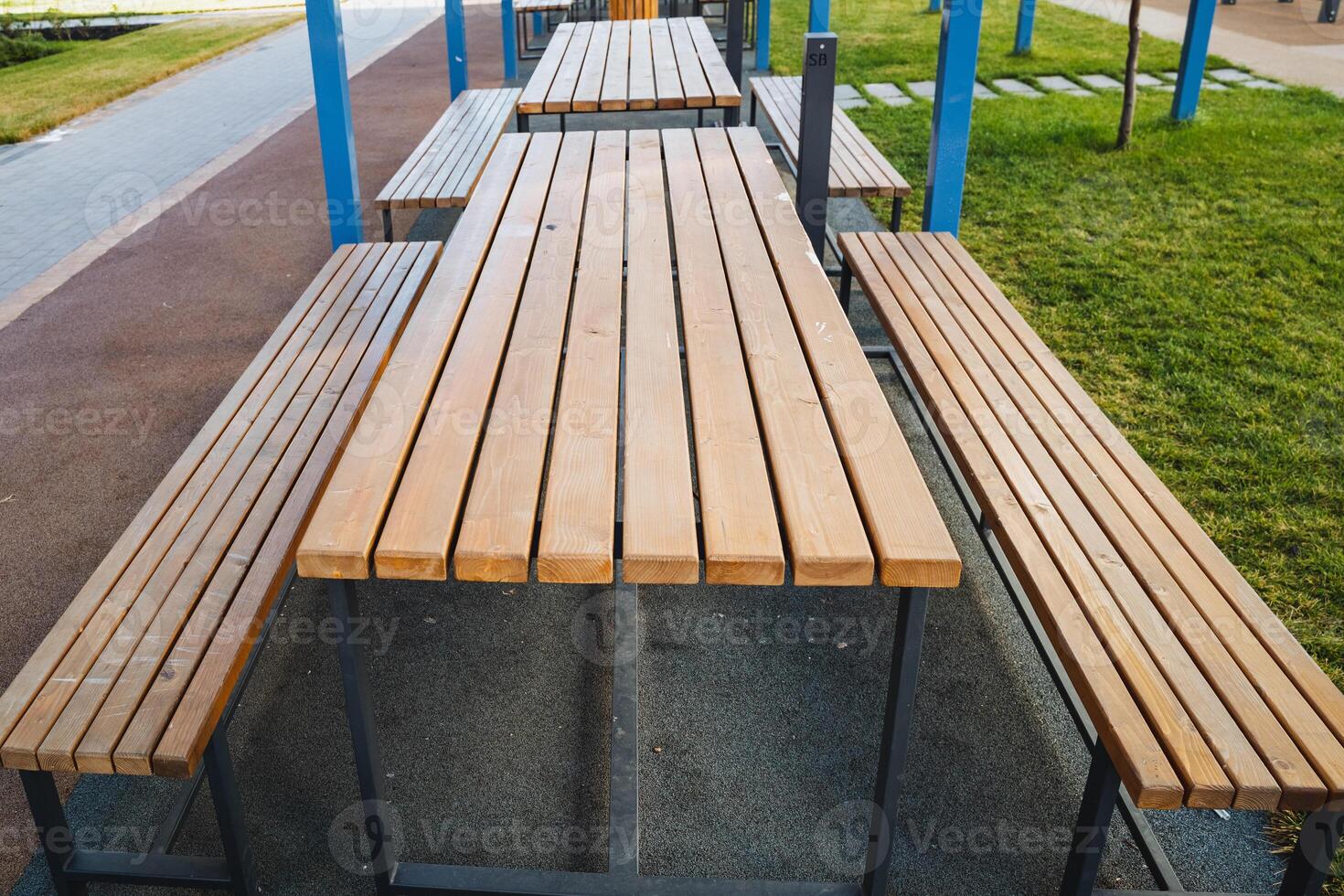A long wooden picnic table with benches in a park photo