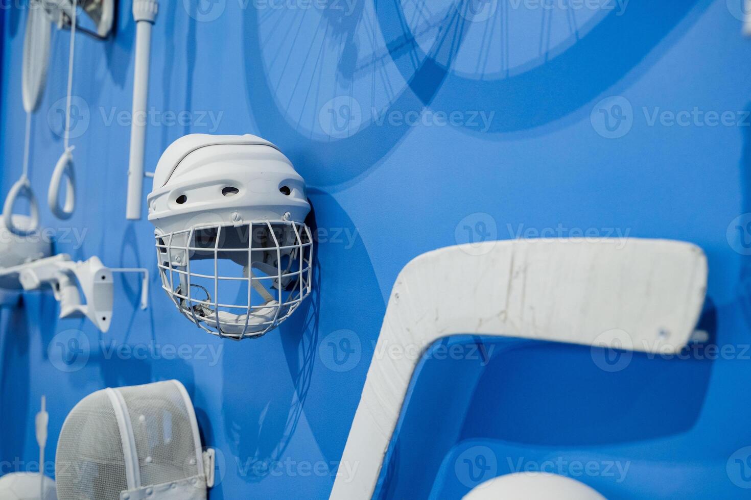 A striking blue wall displays a vibrant hockey helmet, highlighting its design. It symbolizes the importance of safety in sports and the need for athletes to prioritize their wellbeing photo