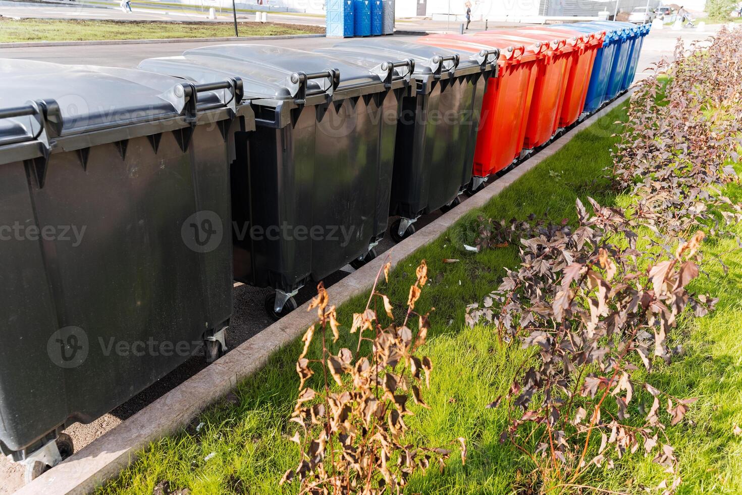 A row of trash cans is neatly lined up along the side of the road, patiently waiting to be emptied. This arrangement helps keep the area tidy and underscores the significance of cleanliness photo