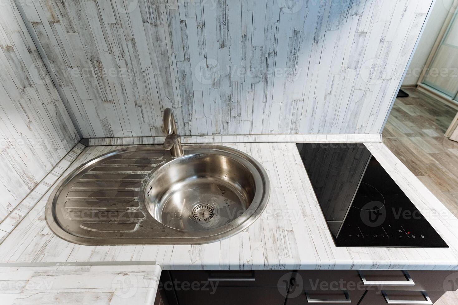 This is a kitchen that features both a sink for washing dishes and a stove top oven for cooking various meals and dishes, enhancing the functionality and utility of the space photo