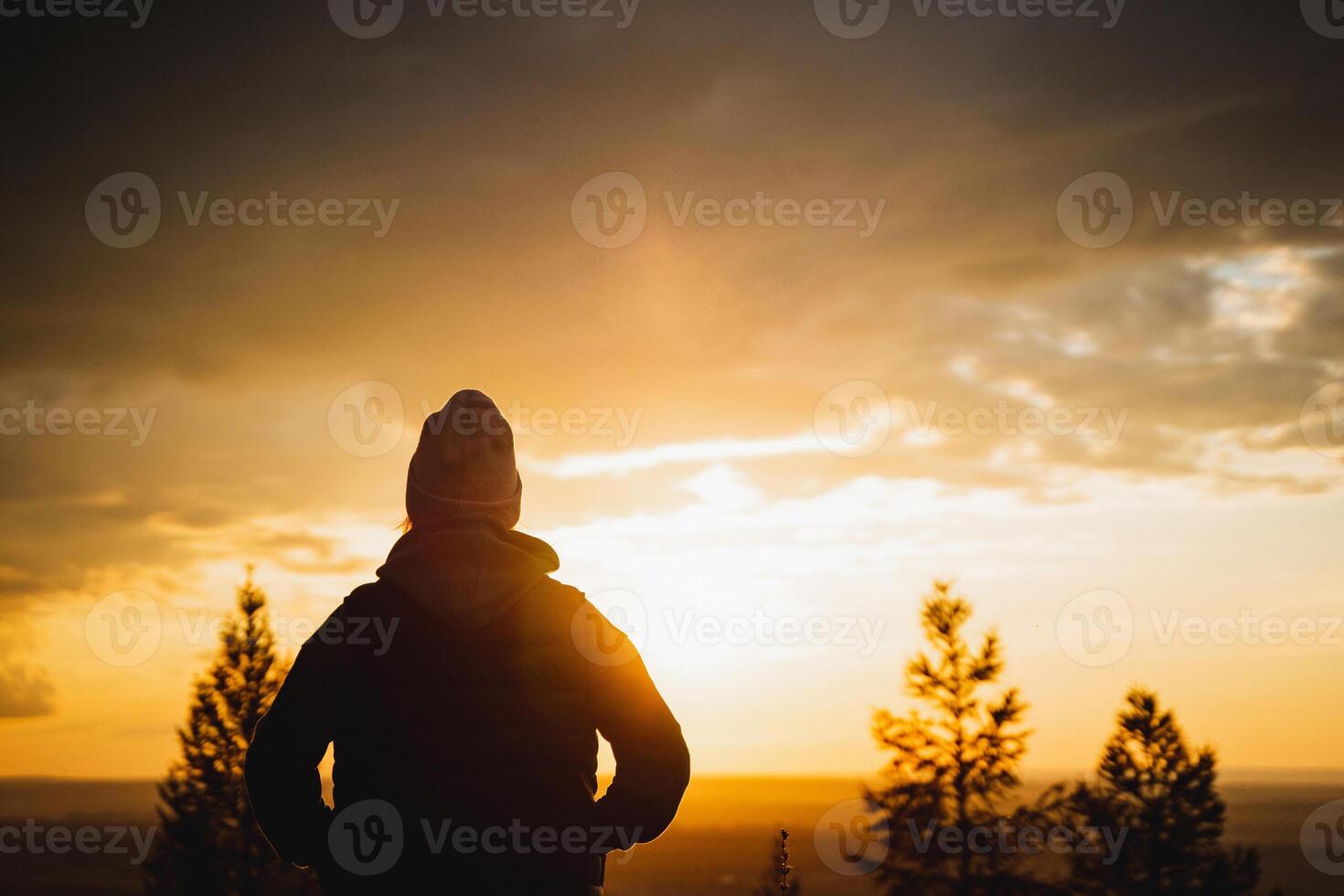 A beautiful silhouette of a person gazing at a stunning sunset, surrounded by a serene landscape that captures the essence of tranquility photo
