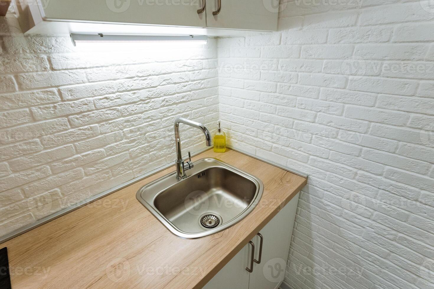 A beautifully designed kitchen sink with a stylish faucet on a polished wooden countertop creates a focal point for any modern cooking space, inspiring culinary creativity photo