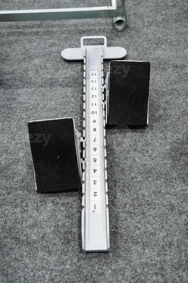 This image presents a highly detailed closeup of a starting block positioned on a textured carpet, emphasizing its intricate design as well as the surrounding environment and context photo