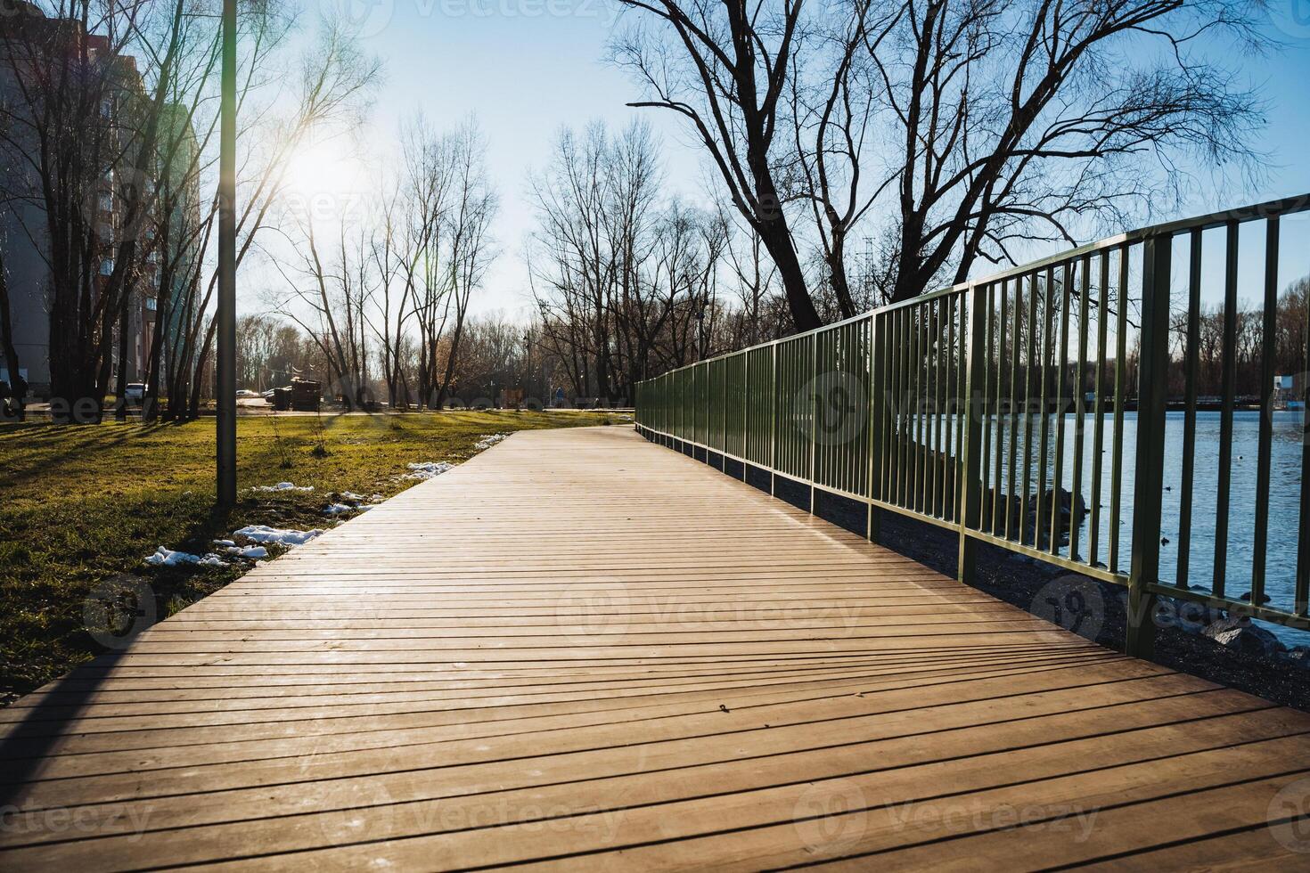 There is a beautiful wooden bridge that gracefully leads to a serene lake nestled within a picturesque park, surrounded by vibrant natural scenery and elements of nature photo