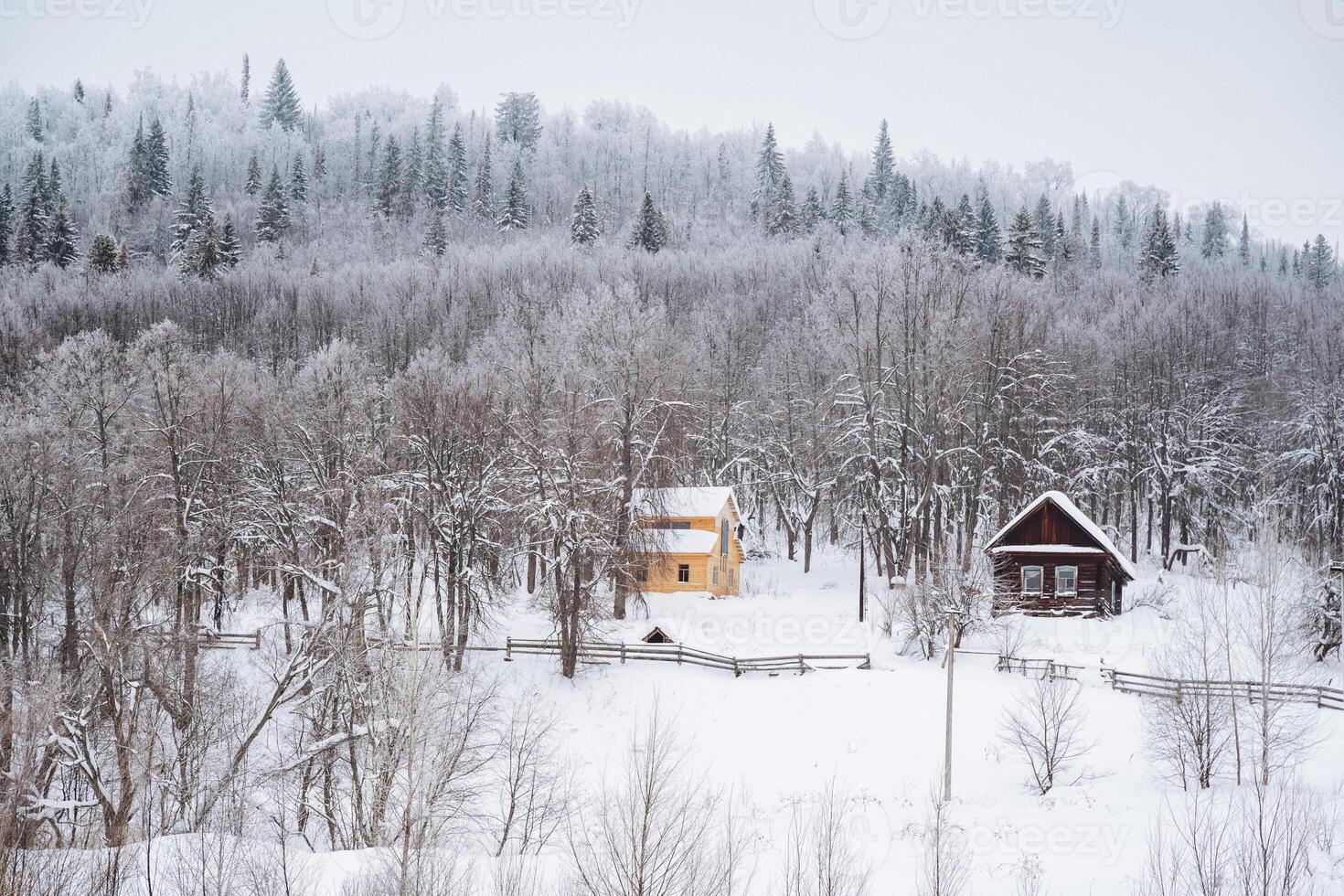 Nestled peacefully in the heart of a snowy and tranquil forest, there exists a delightful little house that warmly beckons to you with its inviting atmosphere during the cold winter months photo
