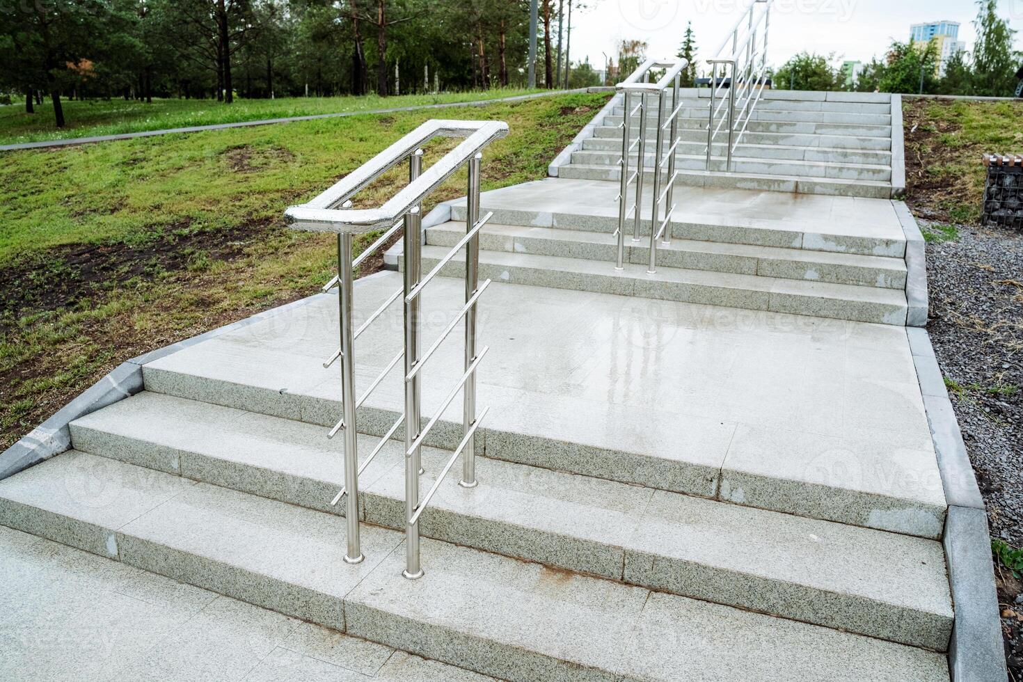 The park offers a tranquil atmosphere with its contemporary stainless steel stair railings, surrounded by lush greenery and tall trees, creating a peaceful and natural setting photo